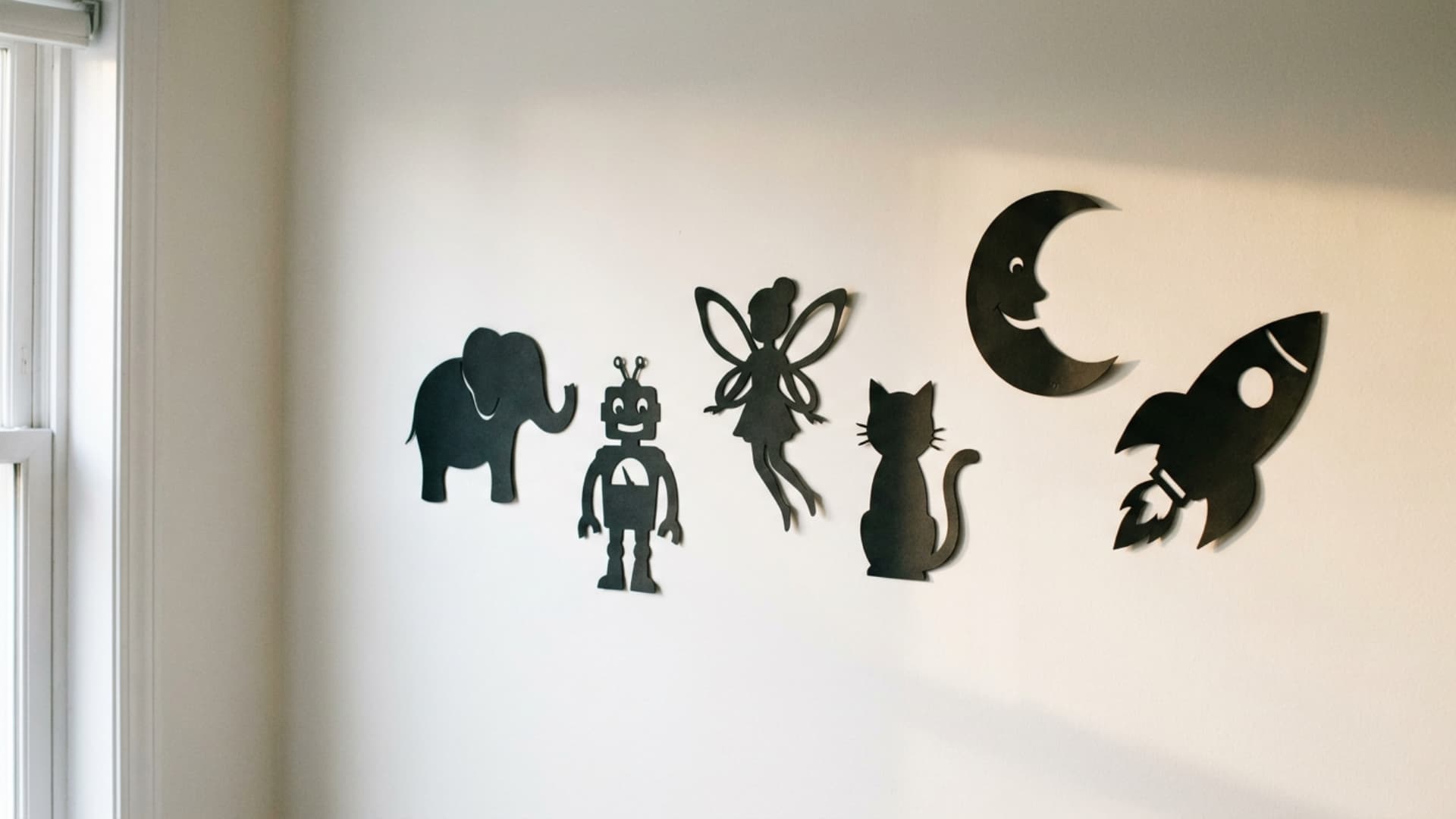 black cardstock character silhouette cutouts arranged on soft white kids bedroom wall