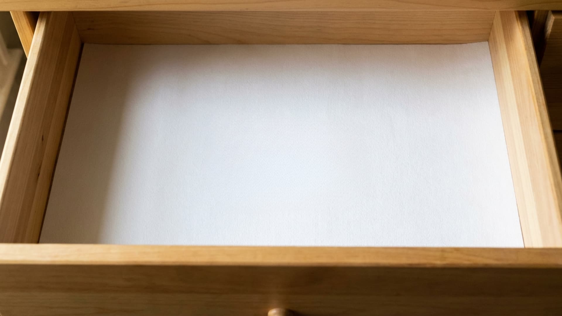 open empty dresser drawer with white liner paper and small handwritten welcome note card
