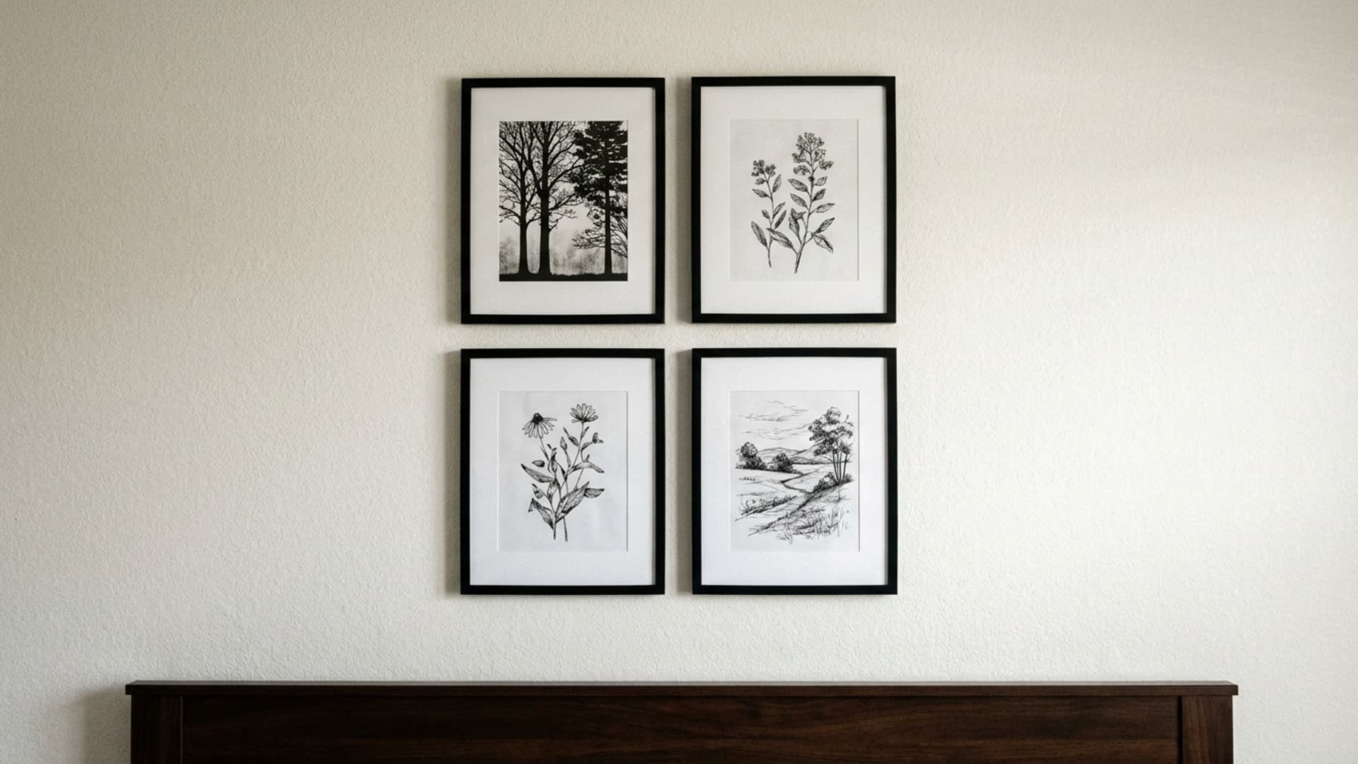 small gallery wall of black and white nature prints in thin black frames above guest bed