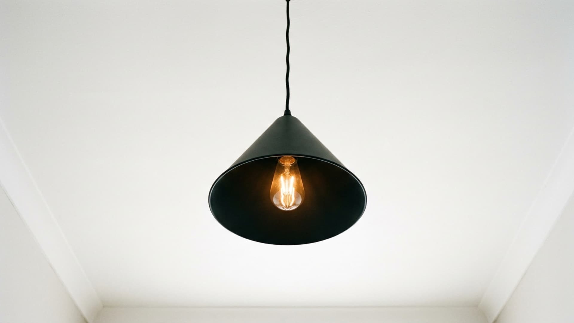 simple matte black pendant light hanging from white ceiling in small guest room