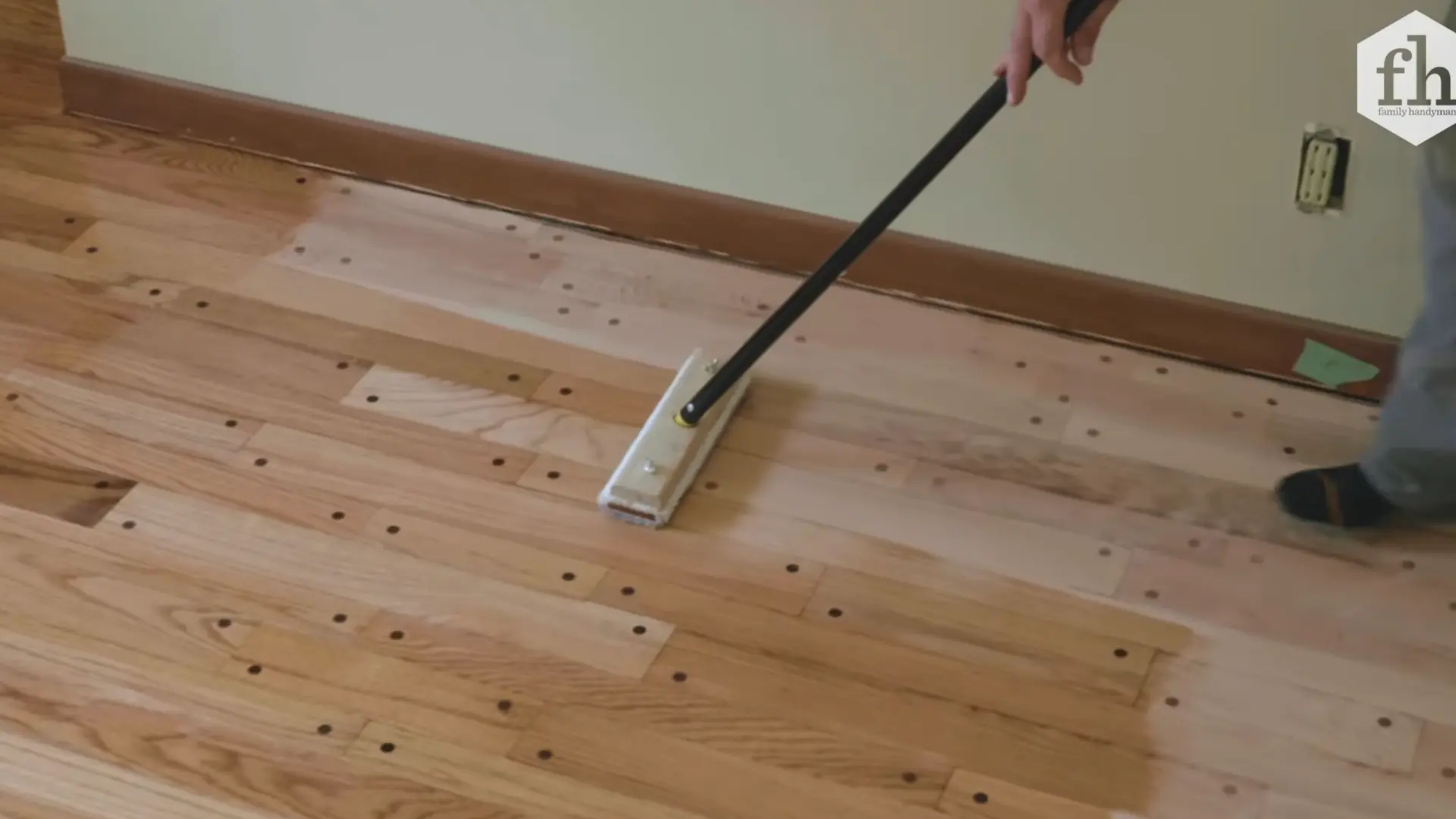 applying first coat of polyurethane finish to hardwood floor with pad applicator