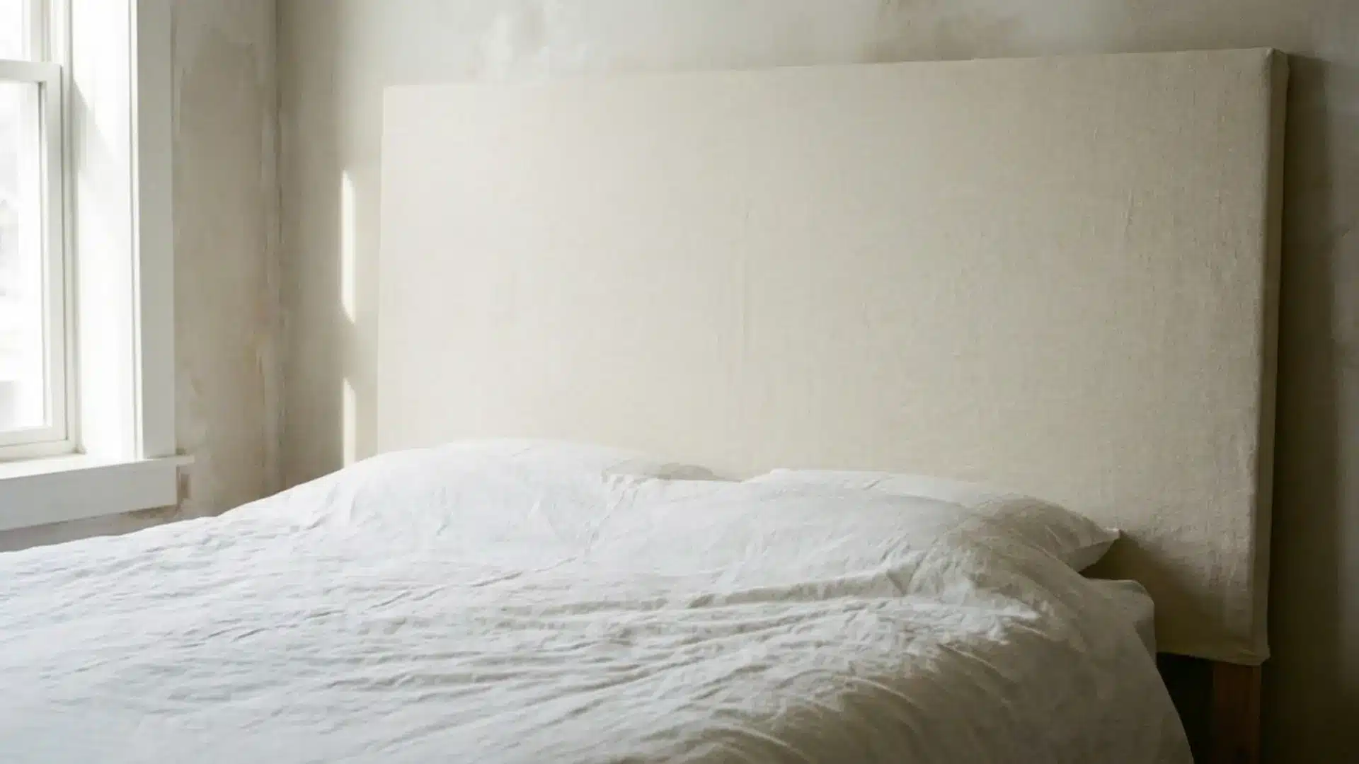 canvas drop cloth headboard behind a bed with white bedding