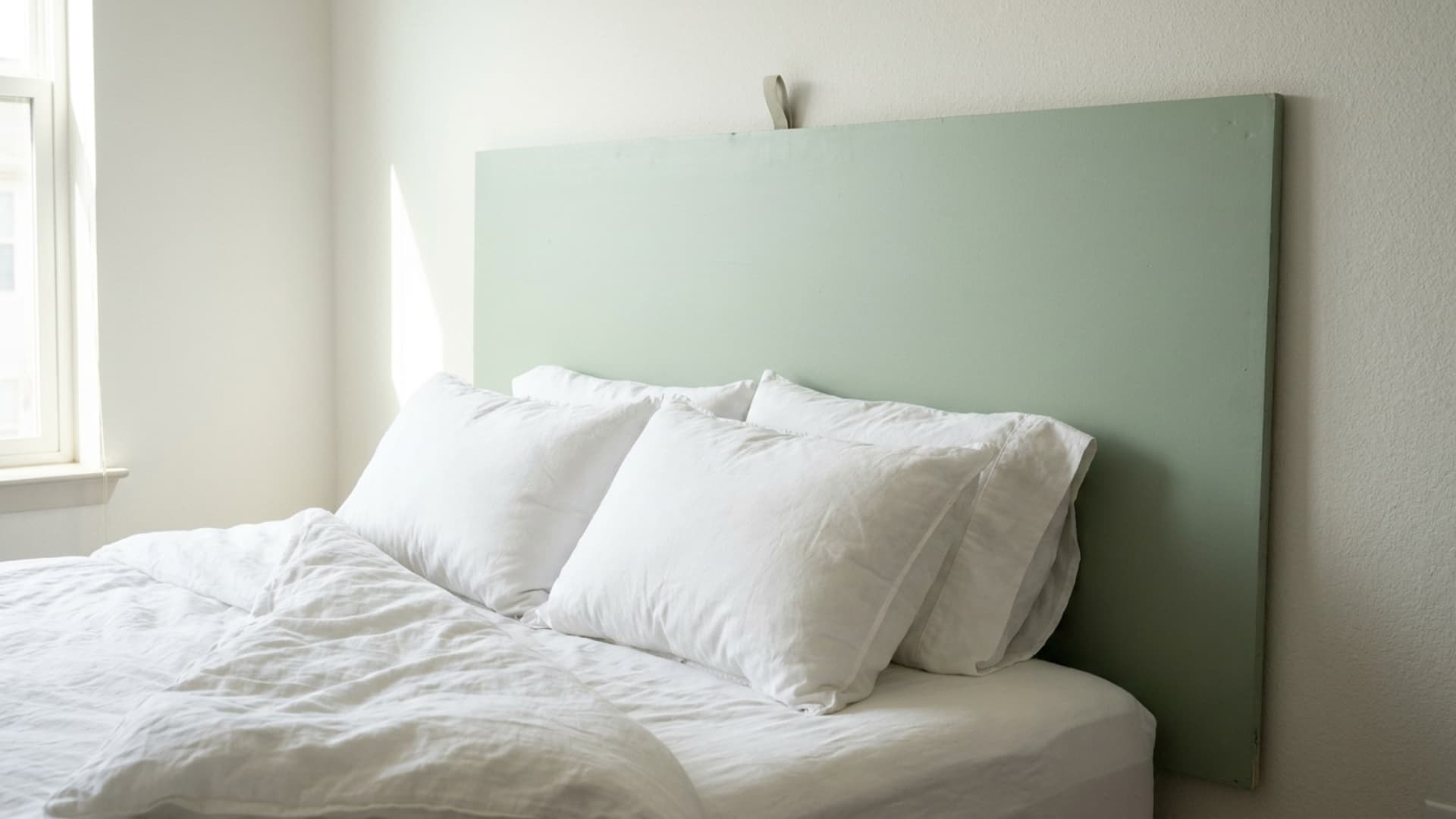 command strip hung headboard with a foam panel behind a bed