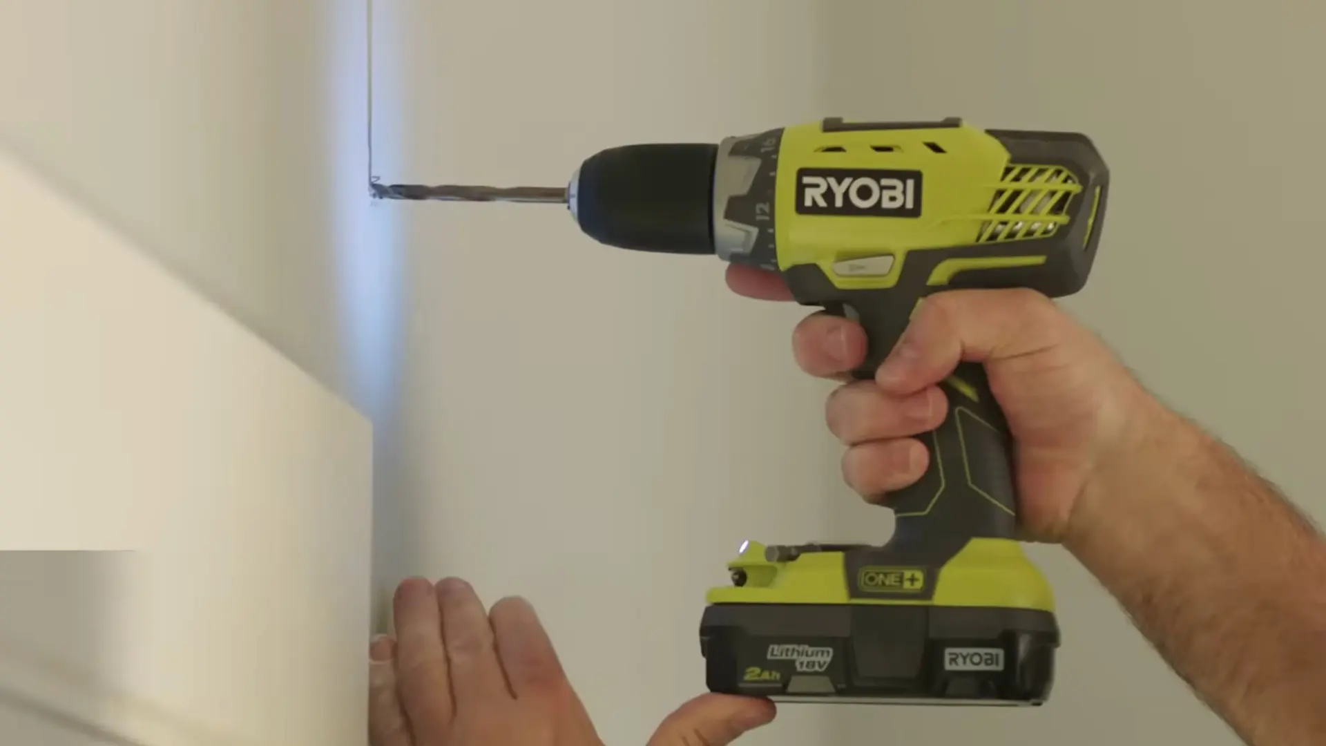 drilling pilot hole into wall with ryobi power drill for curtain rod bracket