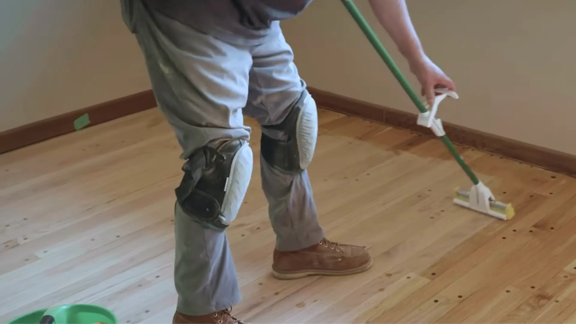 worker damp mopping hardwood floor to remove dust before applying finish