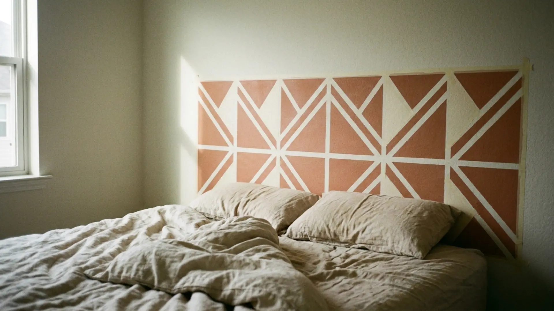 geometric stencil headboard with triangle pattern behind a bed