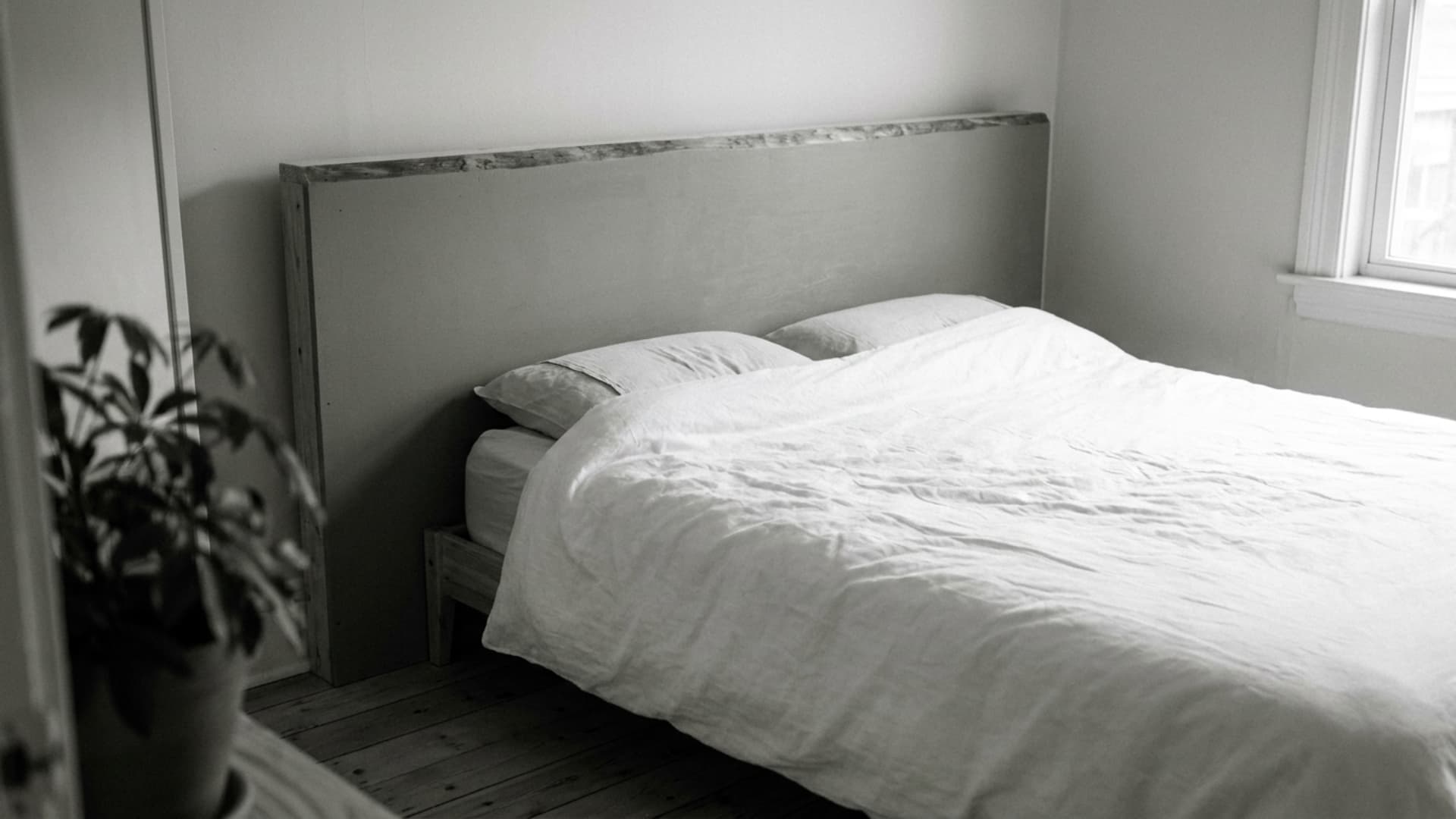 monochrome plywood headboard in sage green behind a bed