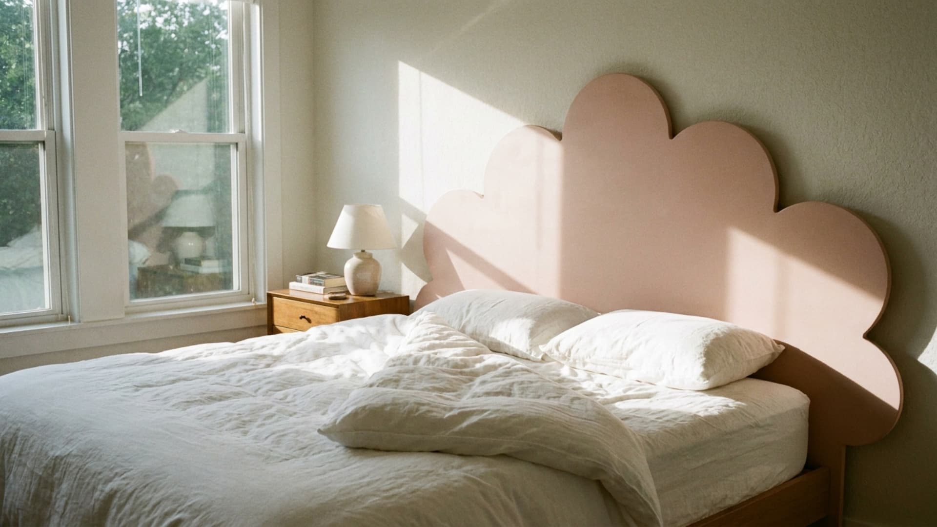 oversized scalloped headboard in blush pink behind a bed