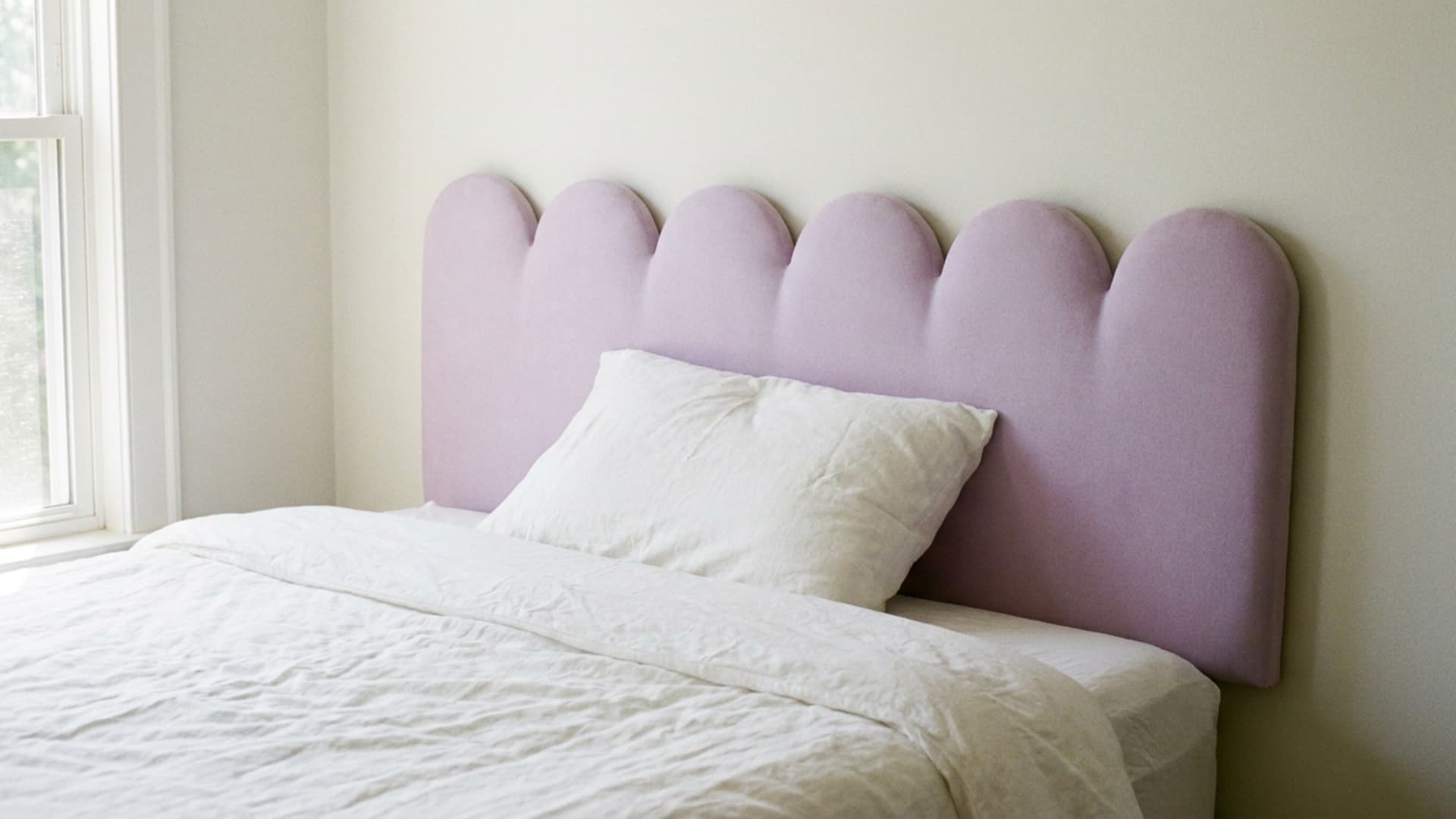 pastel scalloped headboard in lavender behind a kids bed