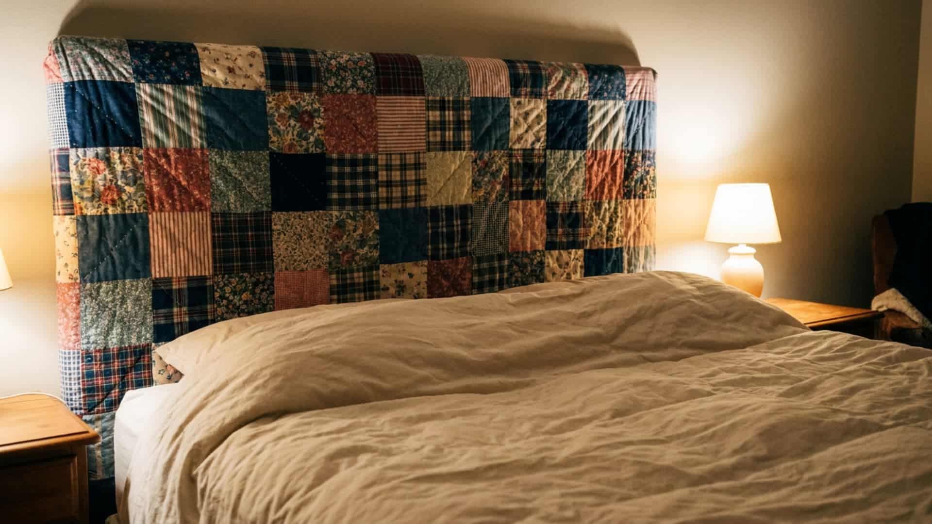 quilted patchwork headboard with mismatched fabric squares behind a bed