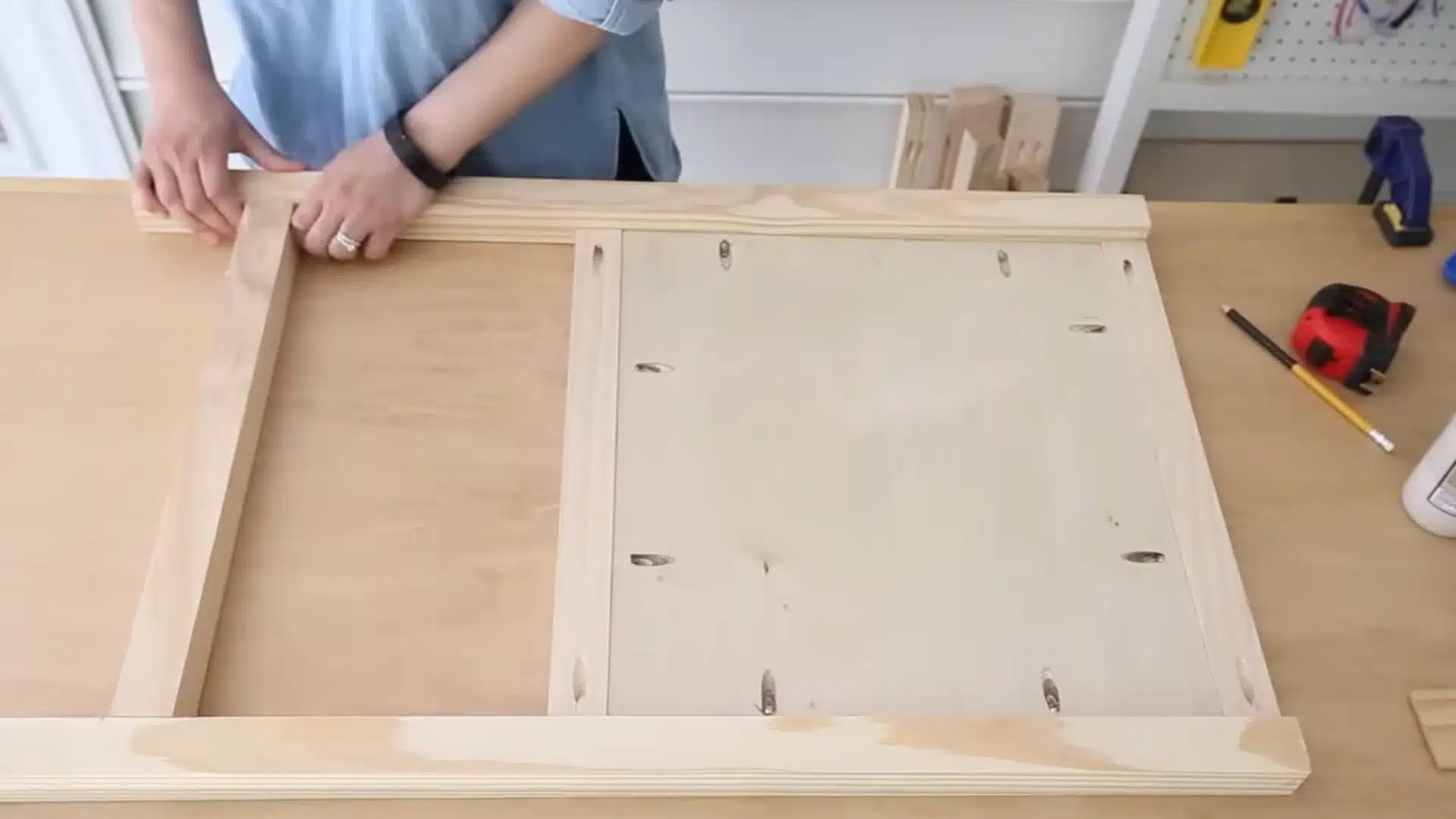 assembling a pine and plywood side frame panel with pocket hole screws on a wood workbench
