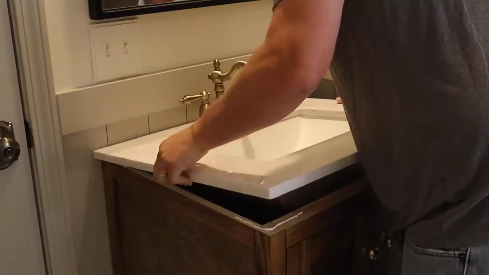 attaching a marble sink top to a finished wood vanity cabinet with silicone caulk along the edge