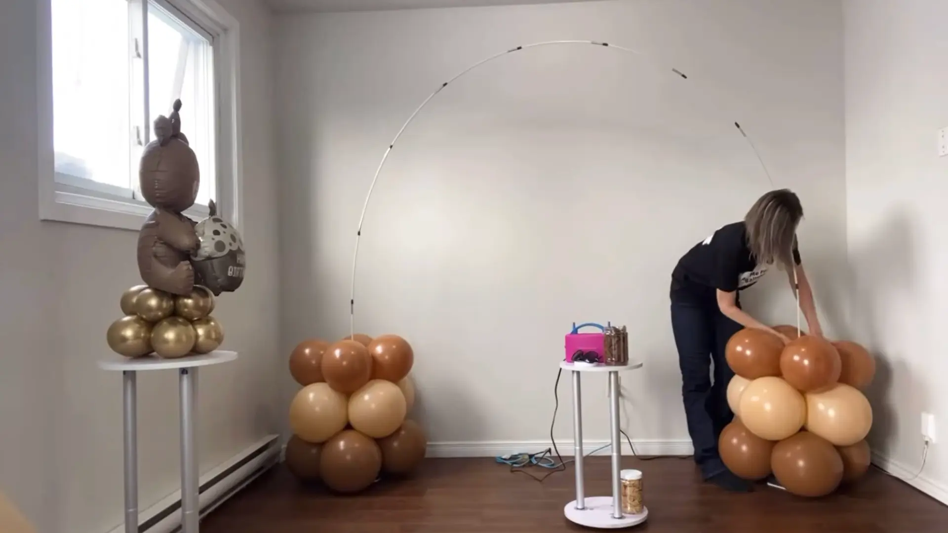 balloon clusters in brown and cream being attached to both sides of the arch frame