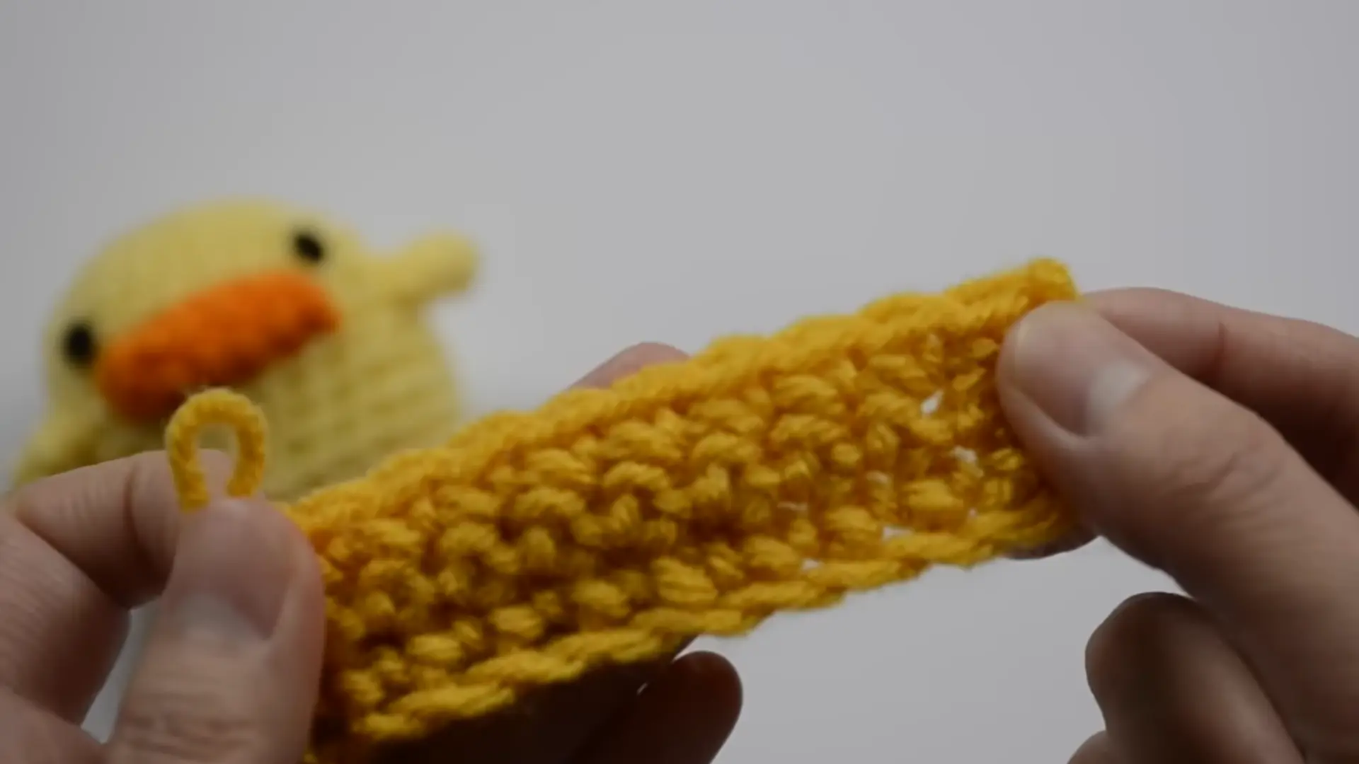 beginner fastening off a crochet project with scissors and a tapestry needle nearby