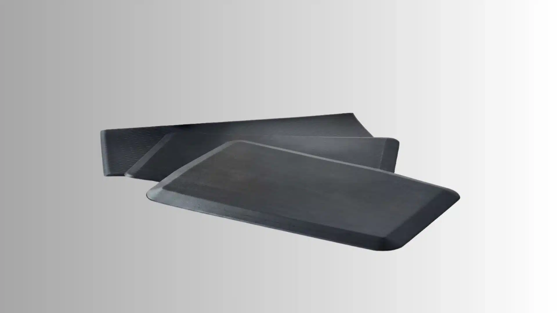 black rectangular anti-fatigue mats with beveled edges arranged on a gradient background
