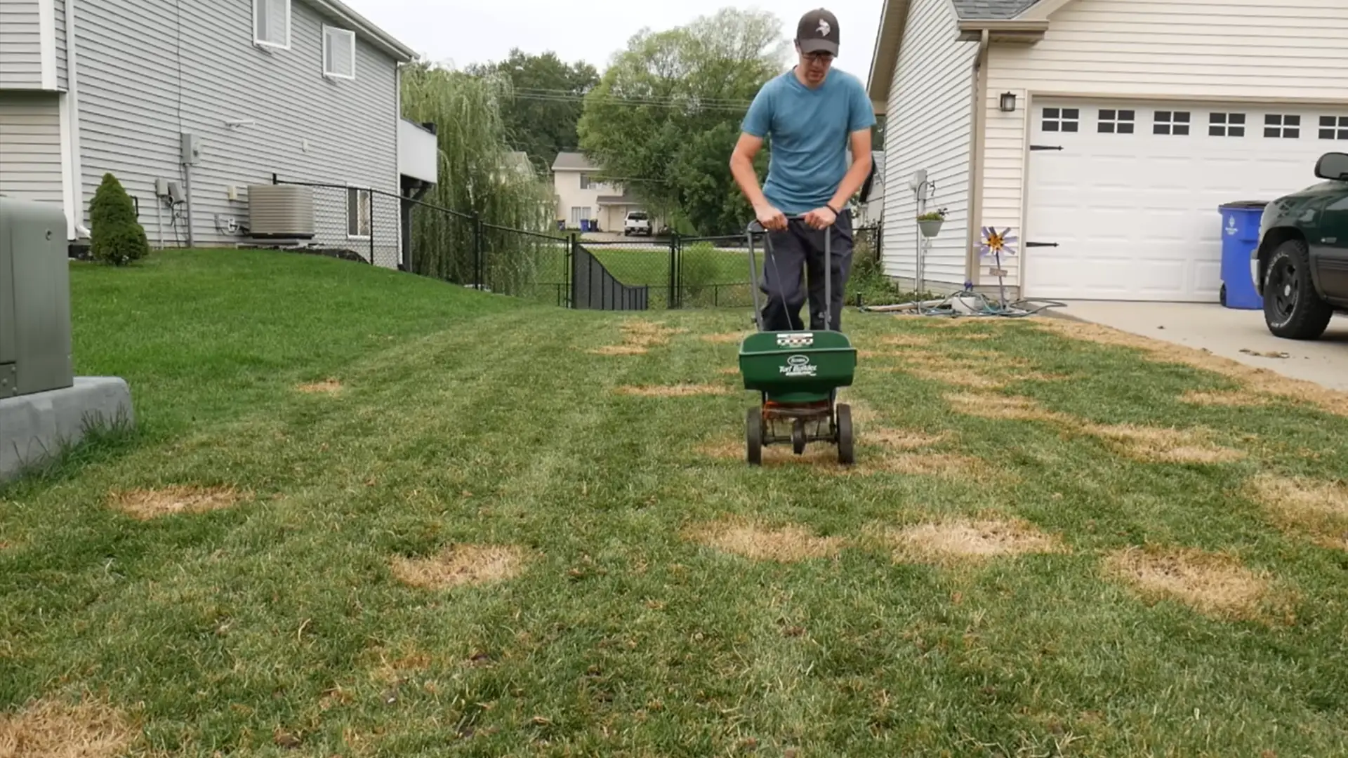 broadcast spreader evenly distributing grass seed across a freshly prepared residential lawn