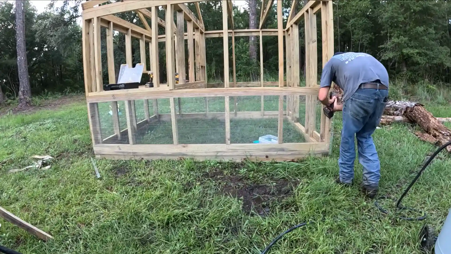 builder installing hardware cloth and chicken wire on the lower walls of a diy chicken coop frame