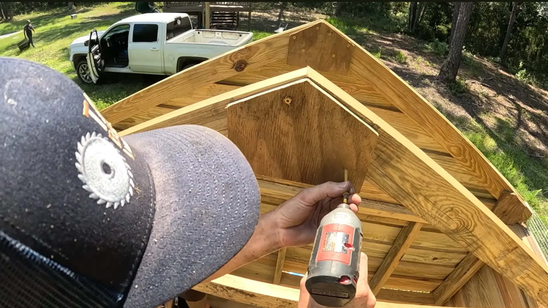 builder using a drill to attach roof rafters and nesting box framing on a diy chicken coop