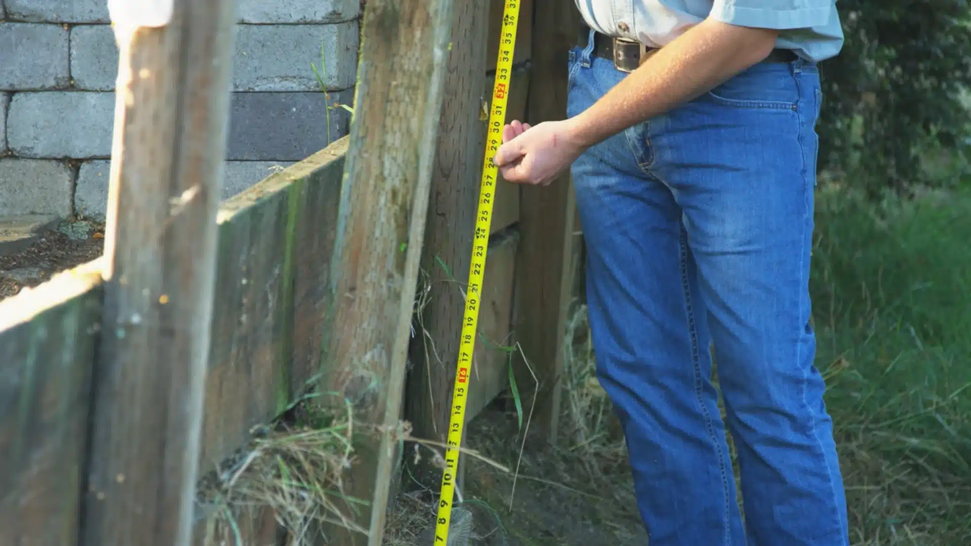 close-up of a tape measure held against a wooden reference post for the wall height