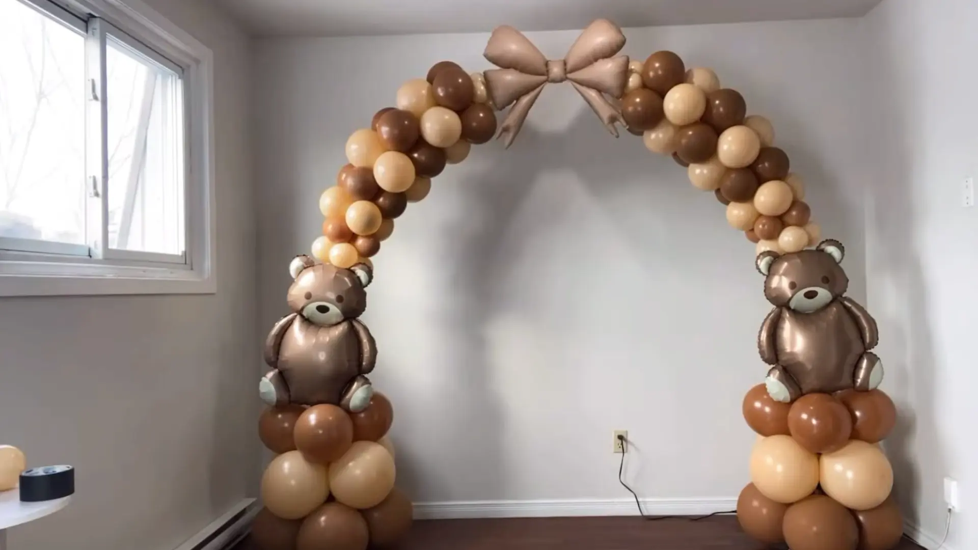 completed balloon arch with teddy bear balloons, brown and cream clusters, and a decorative bow