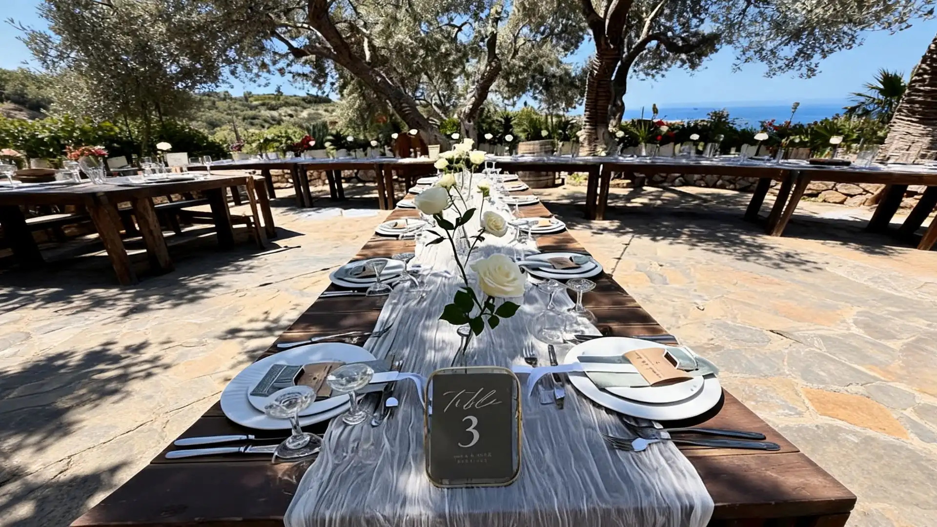 coordinated outdoor wood tables with white roses, matching runners, and a numbered table sign