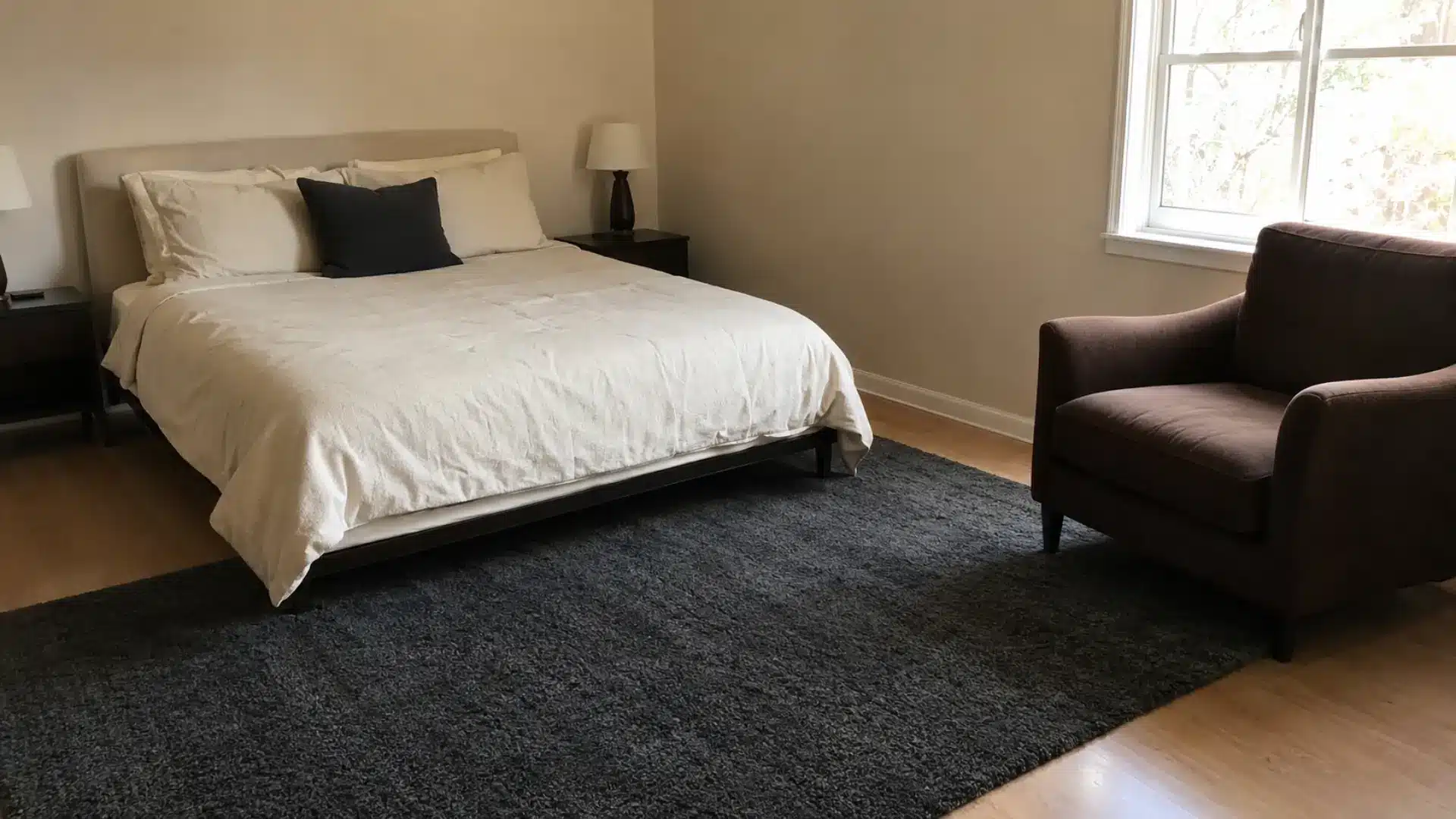 cream bed with dark charcoal shag rug and brown accent chair for a two tone neutral bedroom