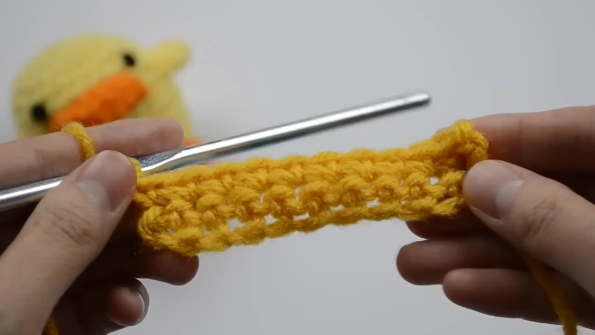 crochet hook inserted into a foundation chain while beginning the first crochet row