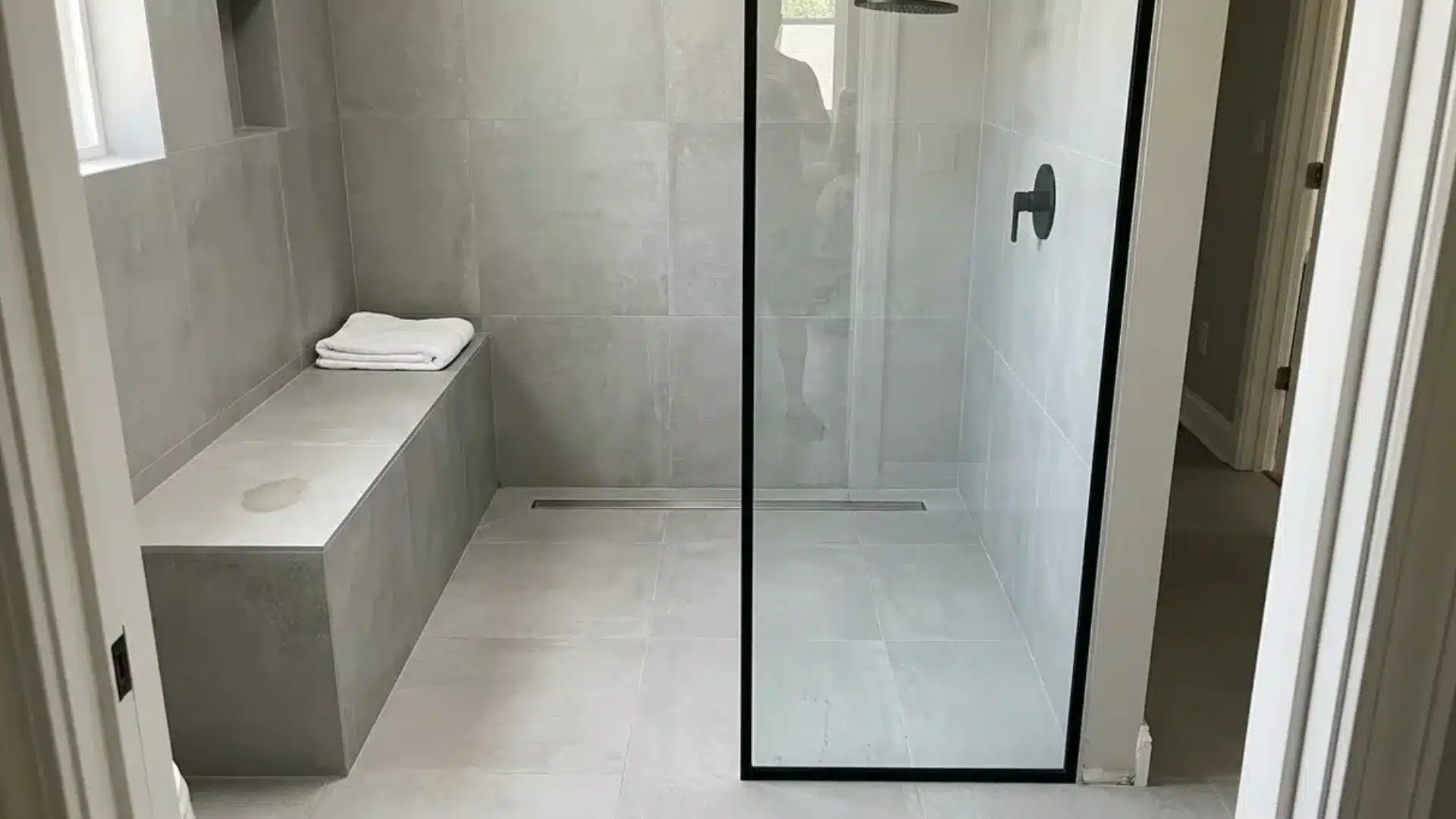 curbless shower with built in tile bench folded towel and black shower fixtures