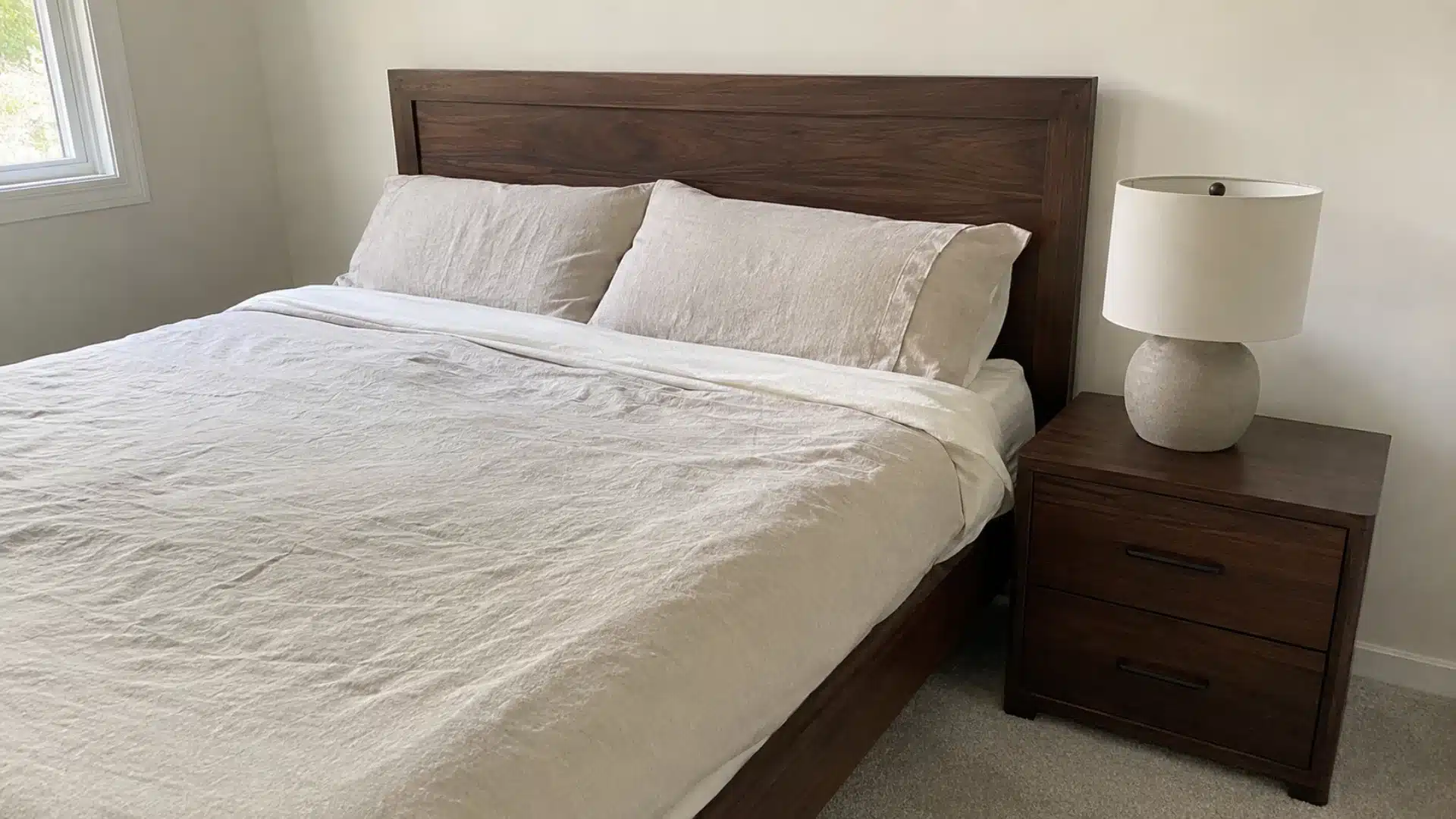 dark walnut wood headboard with cream linen bedding and matching wood nightstand for contrast