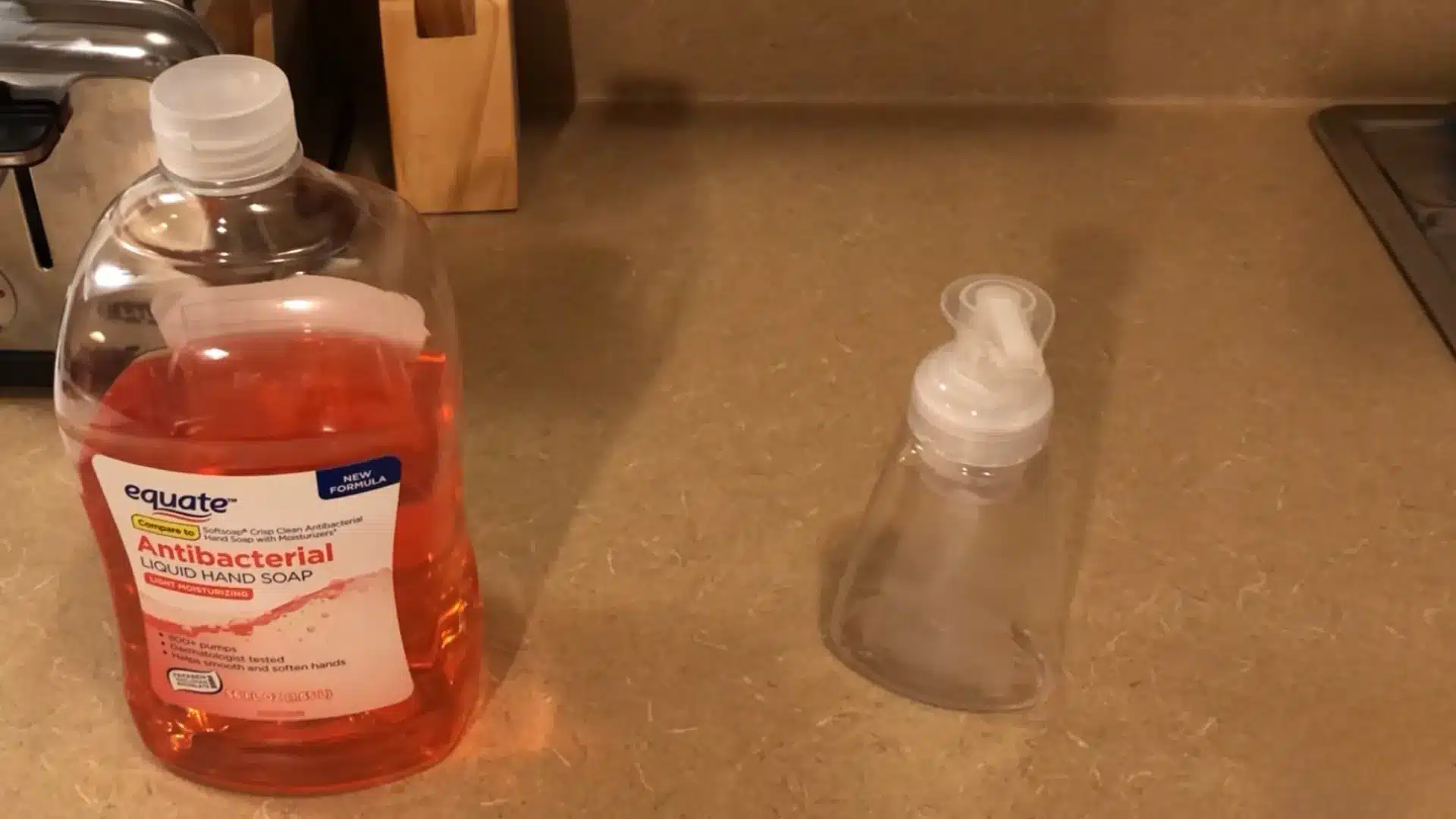 empty foaming soap dispenser next to a bottle of liquid hand soap on a kitchen counter