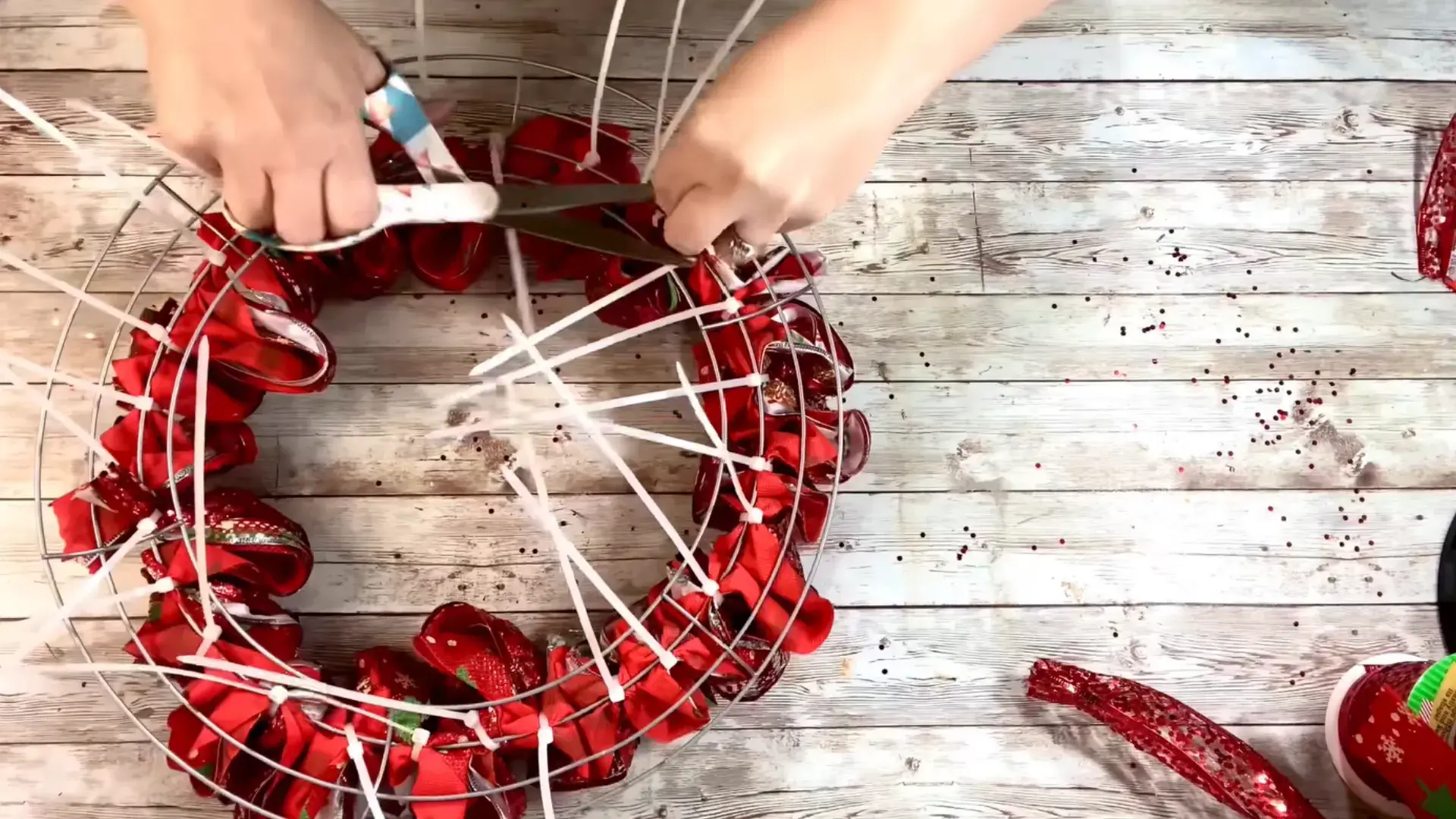excess ribbon and zip tie ends being trimmed from the back of the completed wreath frame