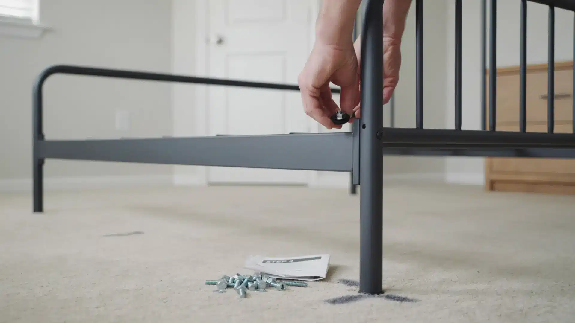 hands inserting a rubber washer at a metal bed frame joint