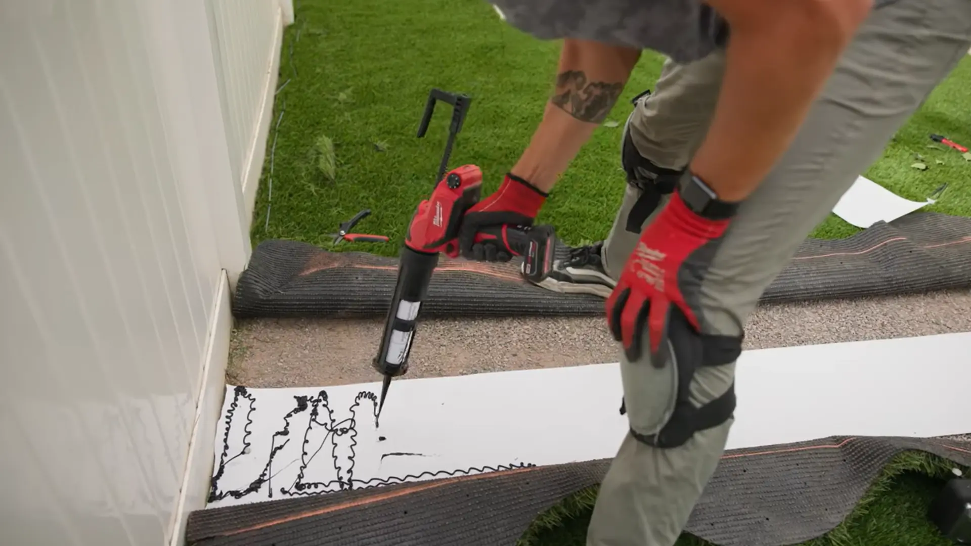 hands joining two sections of artificial grass with seam tape and adhesive for a seamless finish