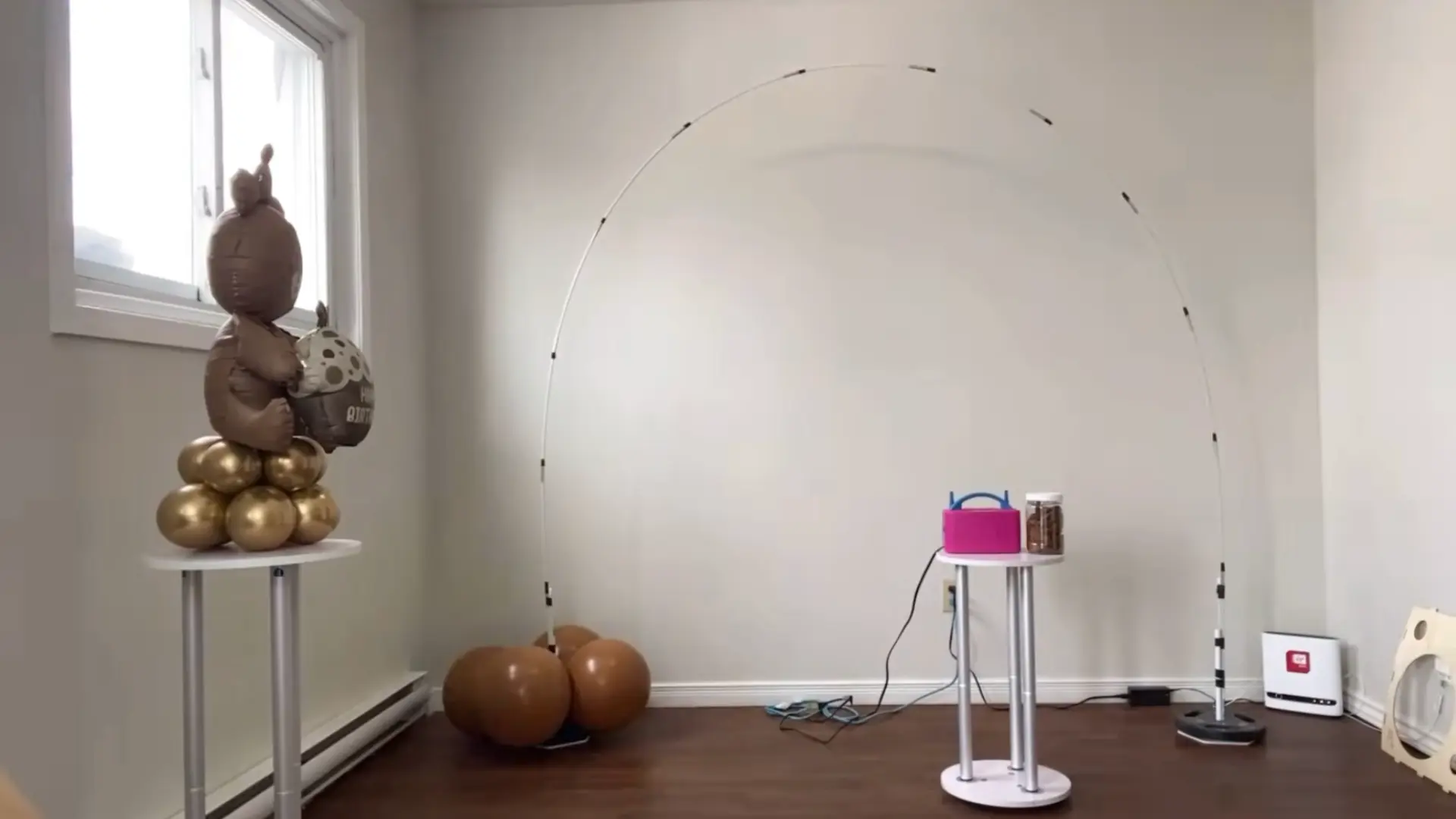 large brown balloons being positioned around the base of a balloon arch stand