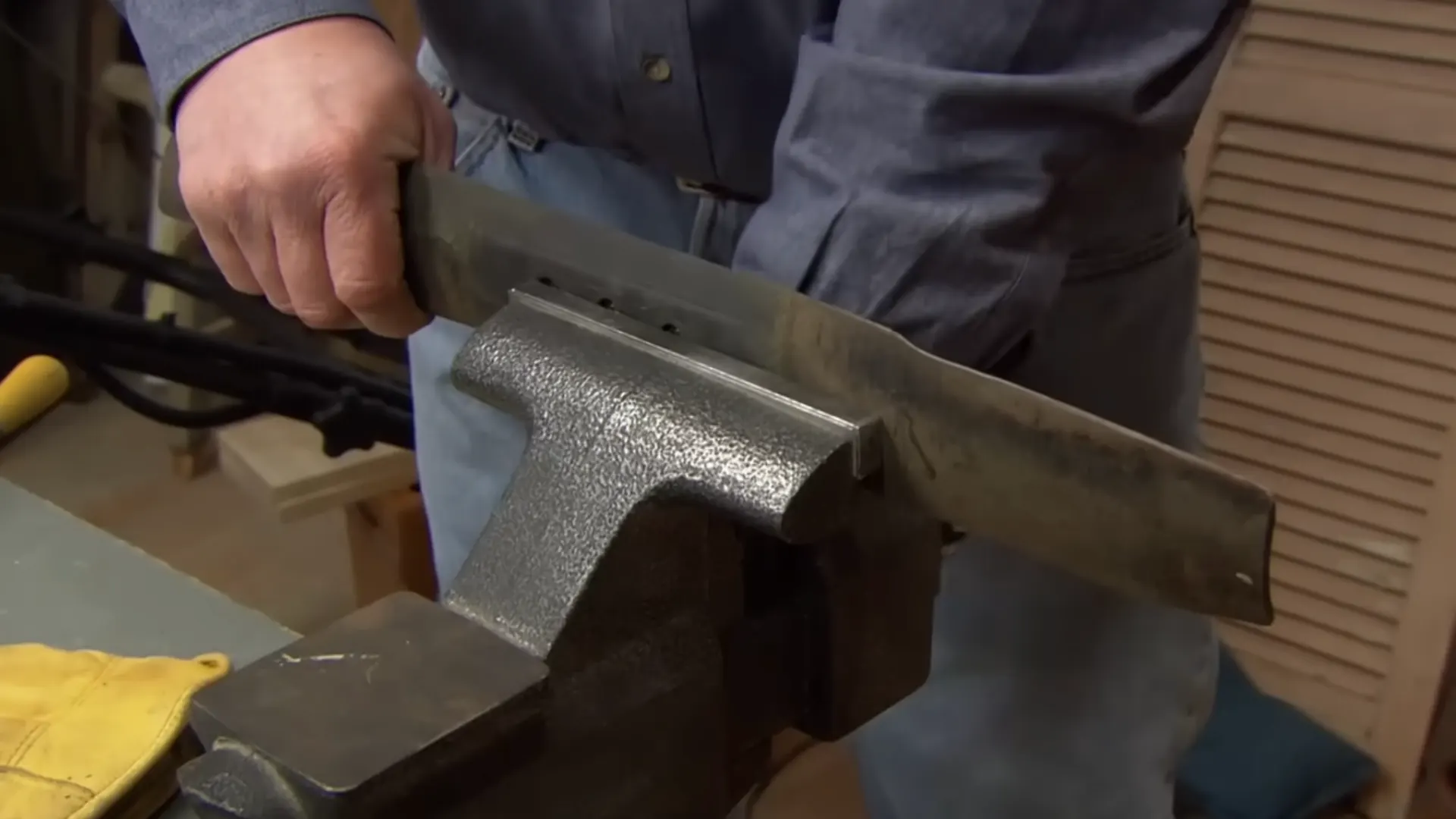 lawn mower blade clamped in a vise, ready for the nut to be removed