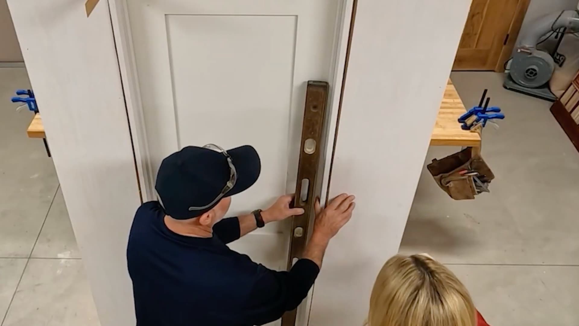 man checking a door jamb against a long level to confirm the hinge side is plumb