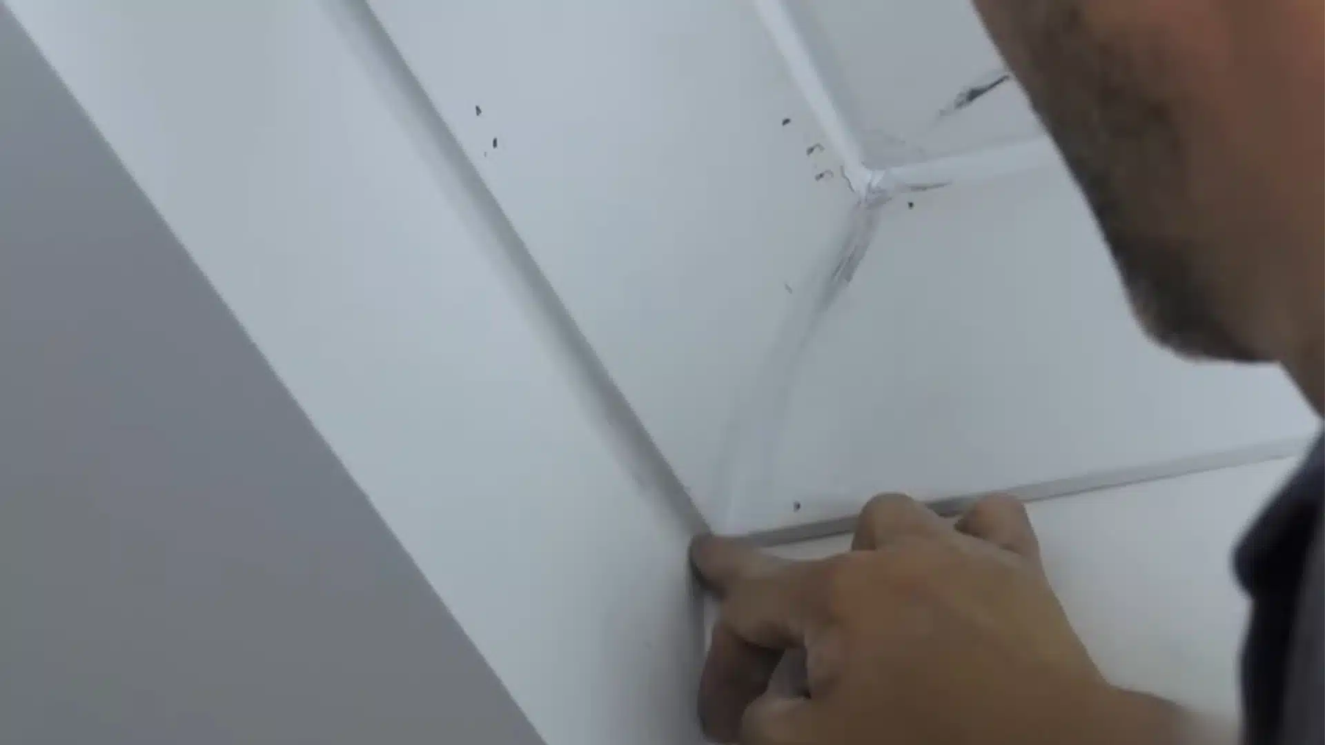 man closely checking crown molding corner joint with fingers for filled nail holes and sanded finish