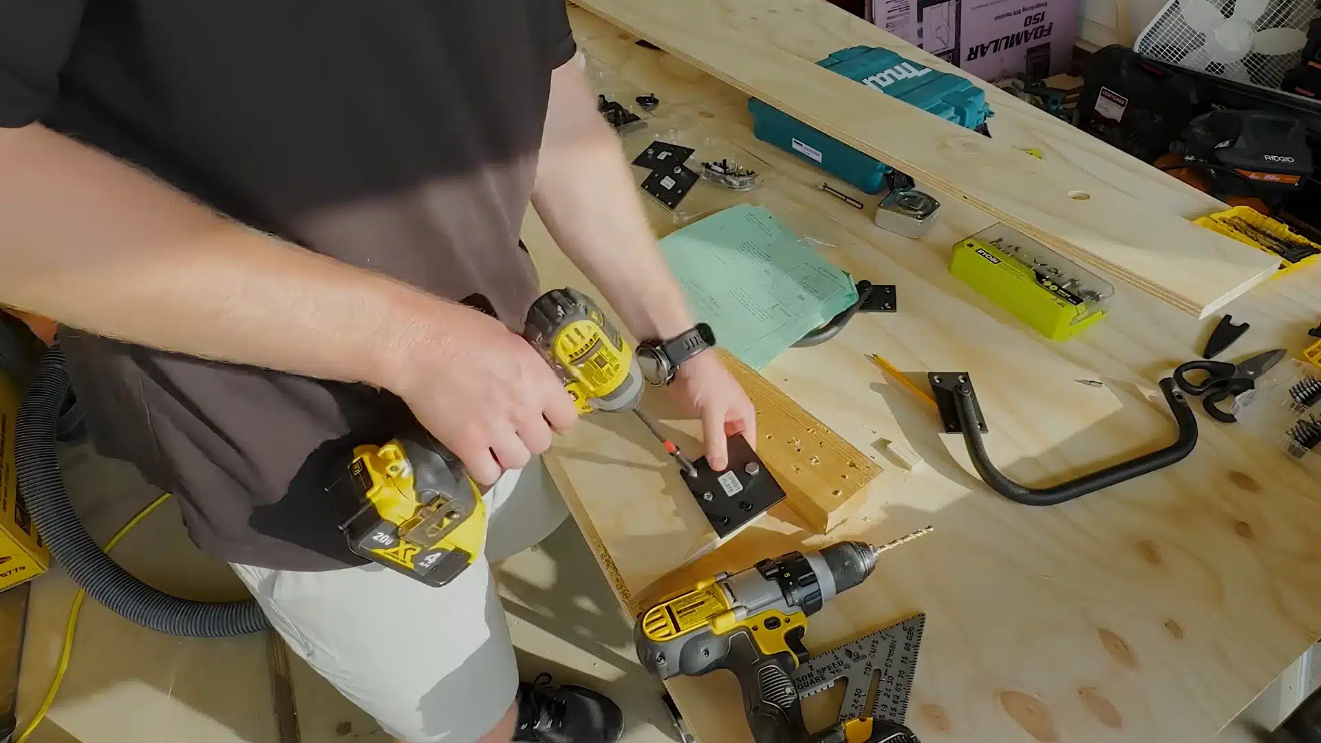 man drilling holes carefully for a pivot plate bracket onto a wooden bed side rail