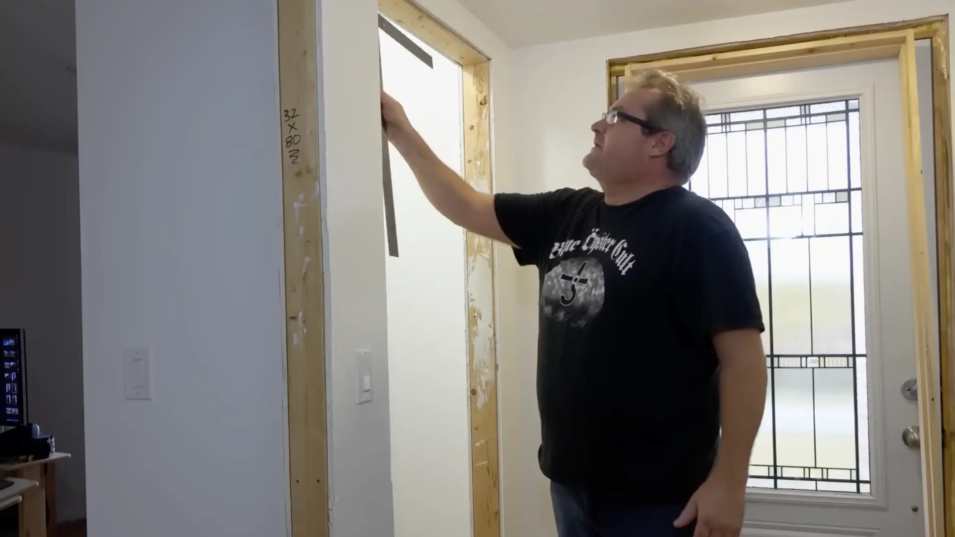 man holding a straightedge against closet door frame to check for square and level