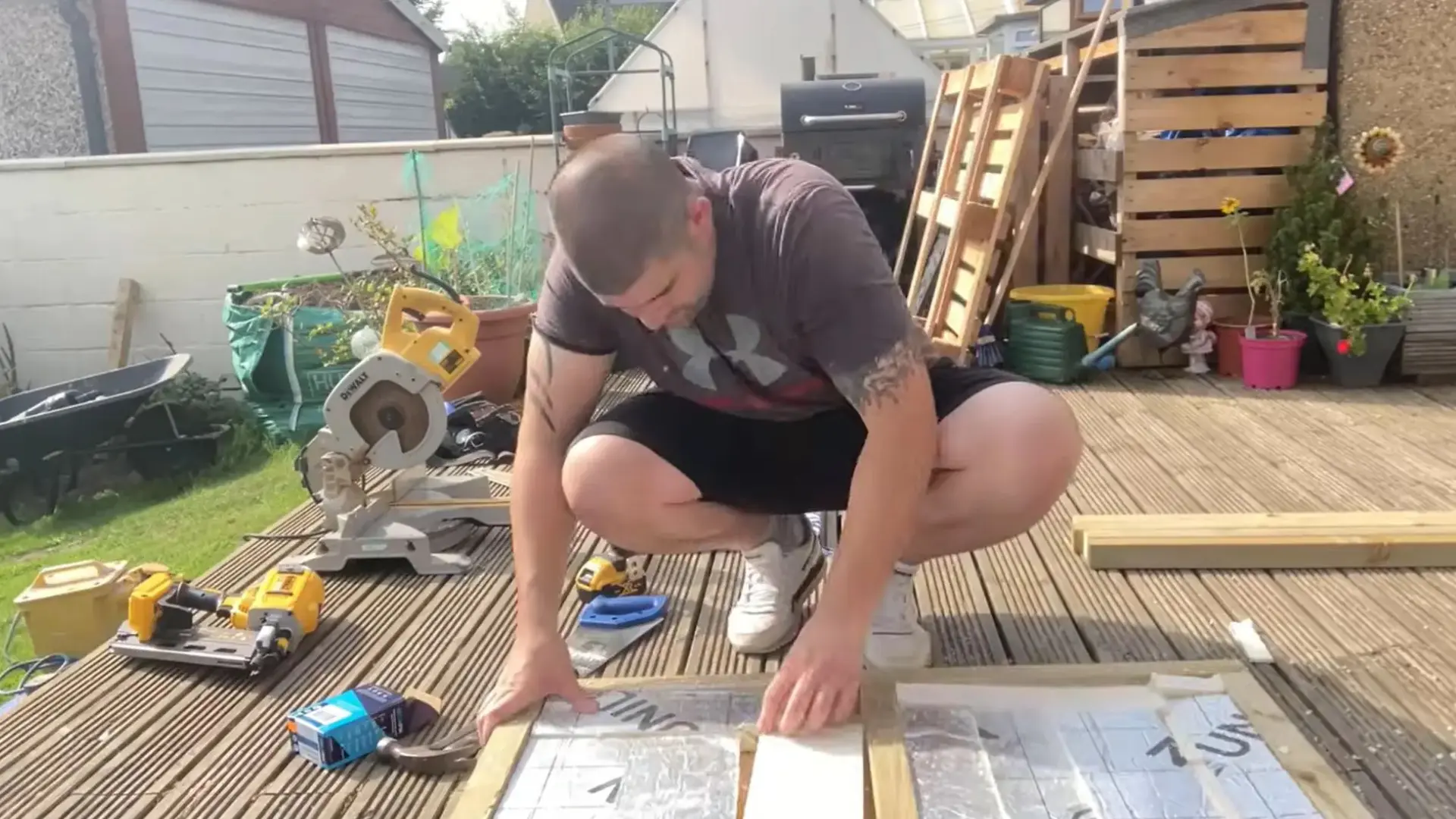 man kneeling down to fit a rigid insulation panel onto a wooden floor frame section