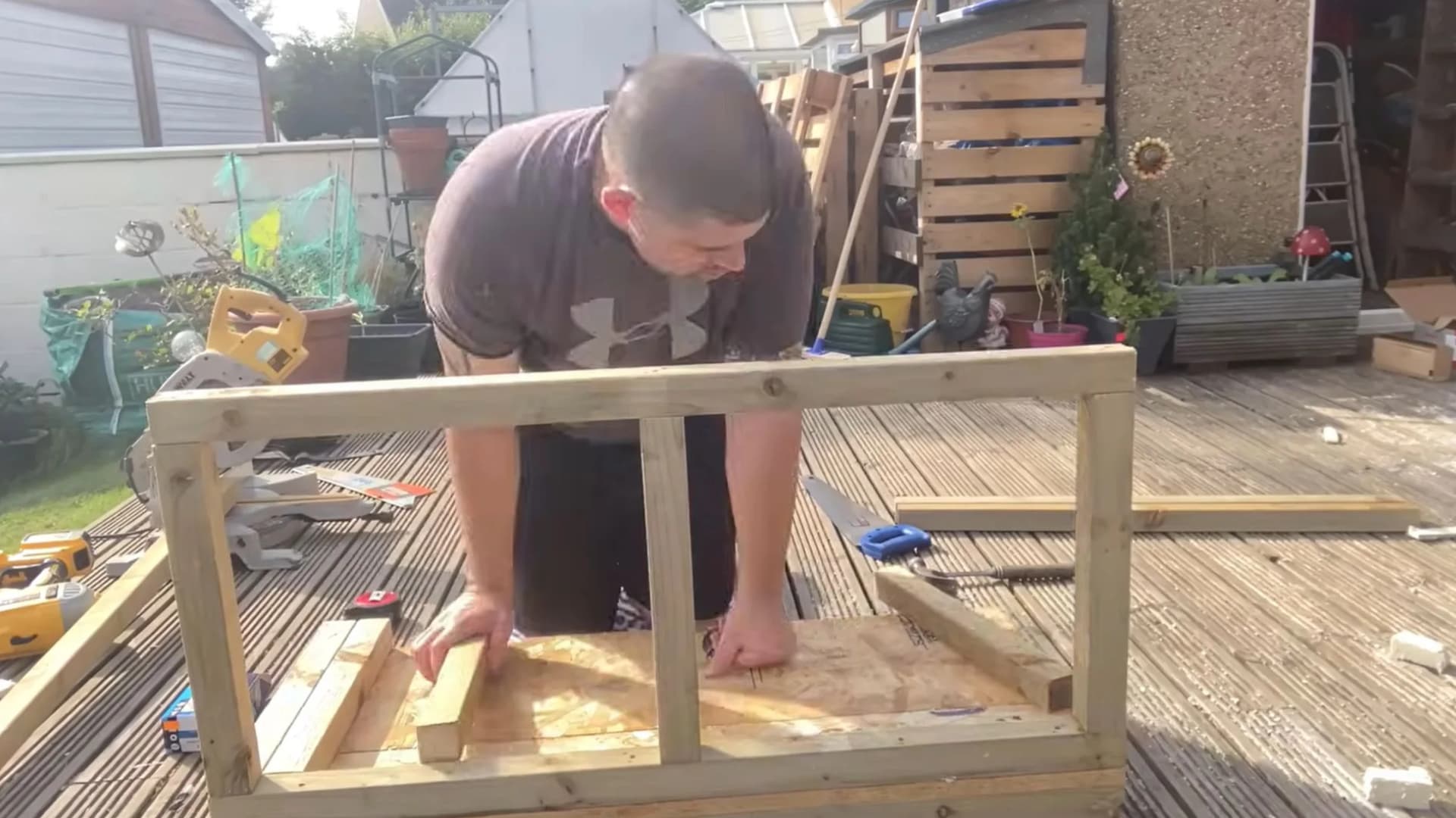 man leaning over to assemble a wooden back wall frame with a center support divider
