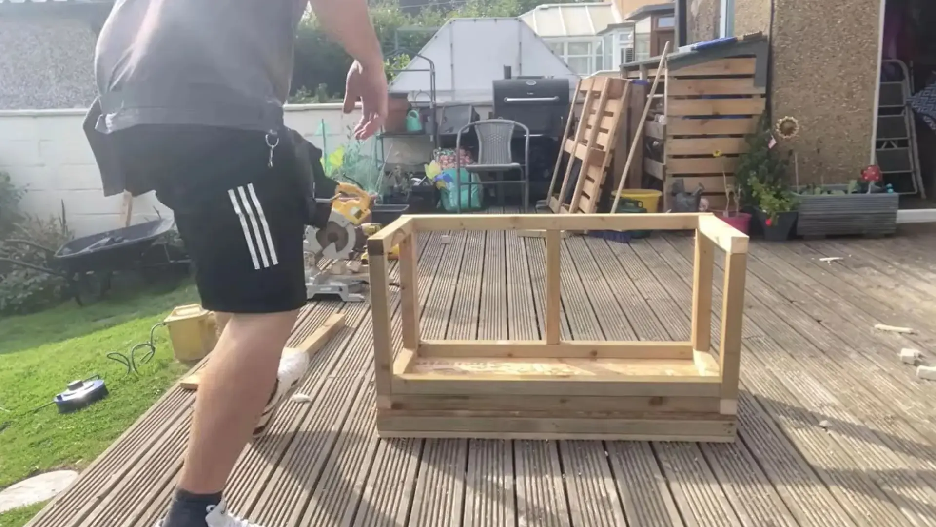 man standing beside a finished wooden box frame with a center divider on decking