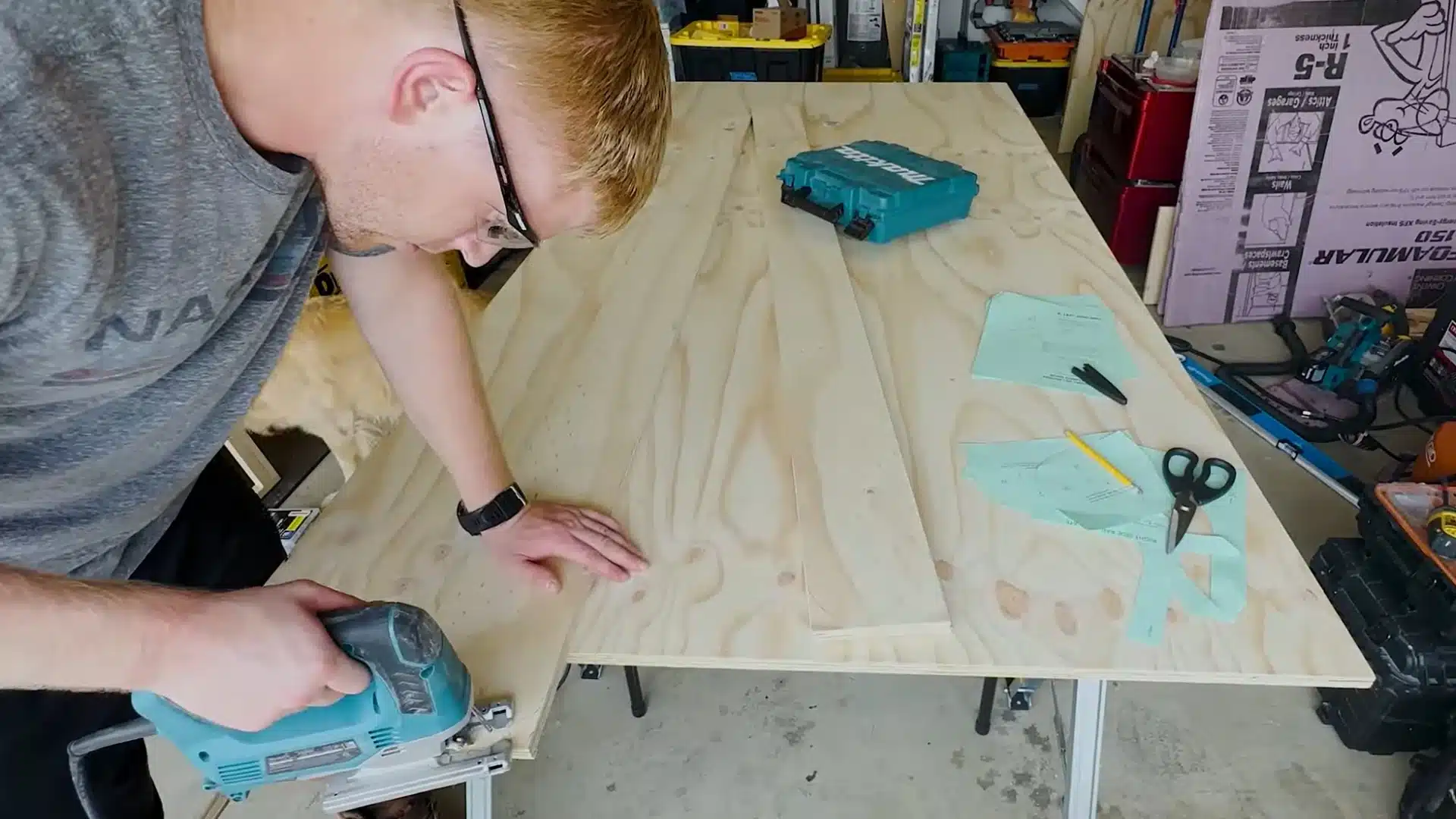 man using a jigsaw to carefully round the curved edge of a plywood bed side rail