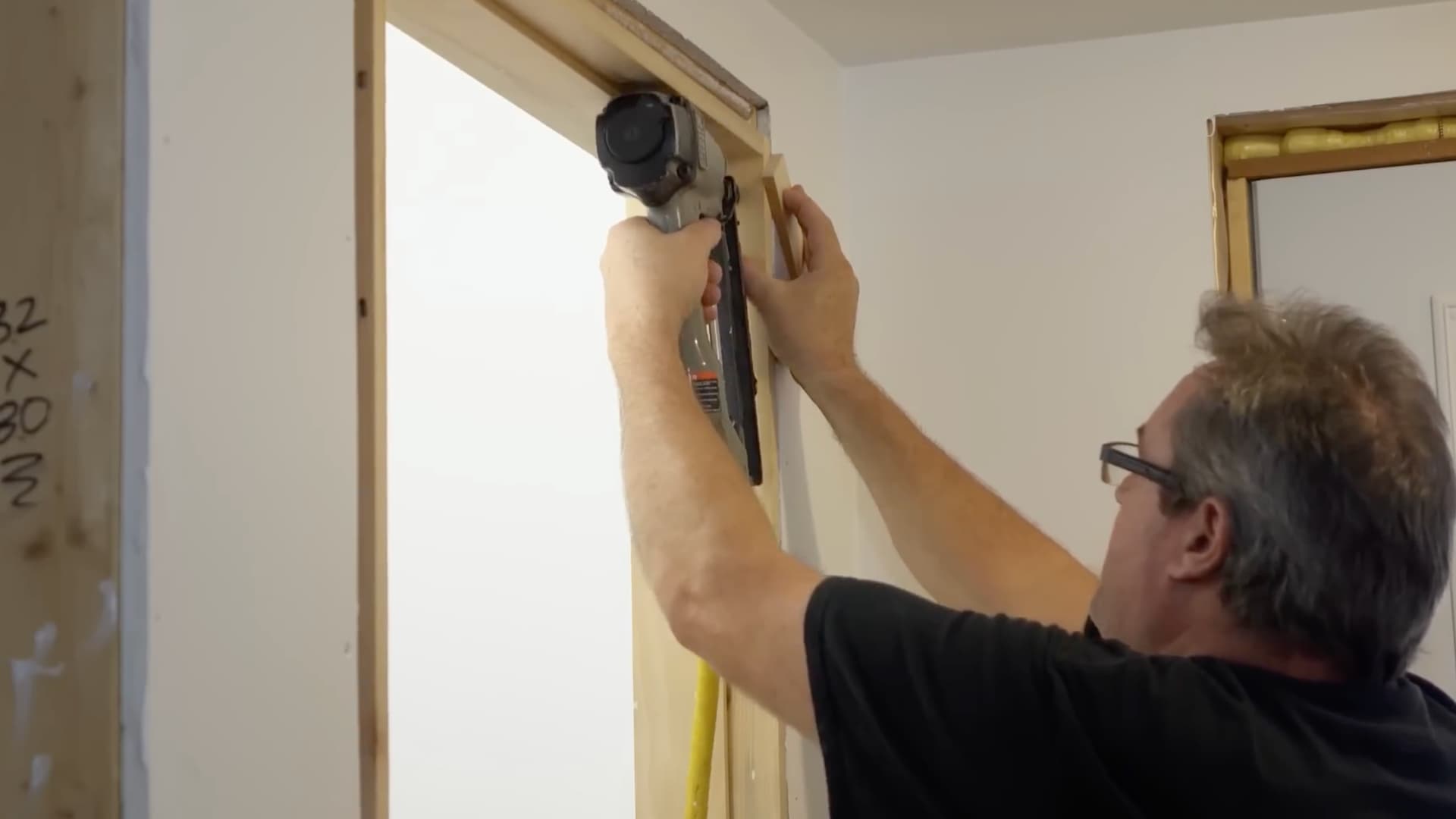 man using nail gun to anchor the hinge side jamb of a closet door frame