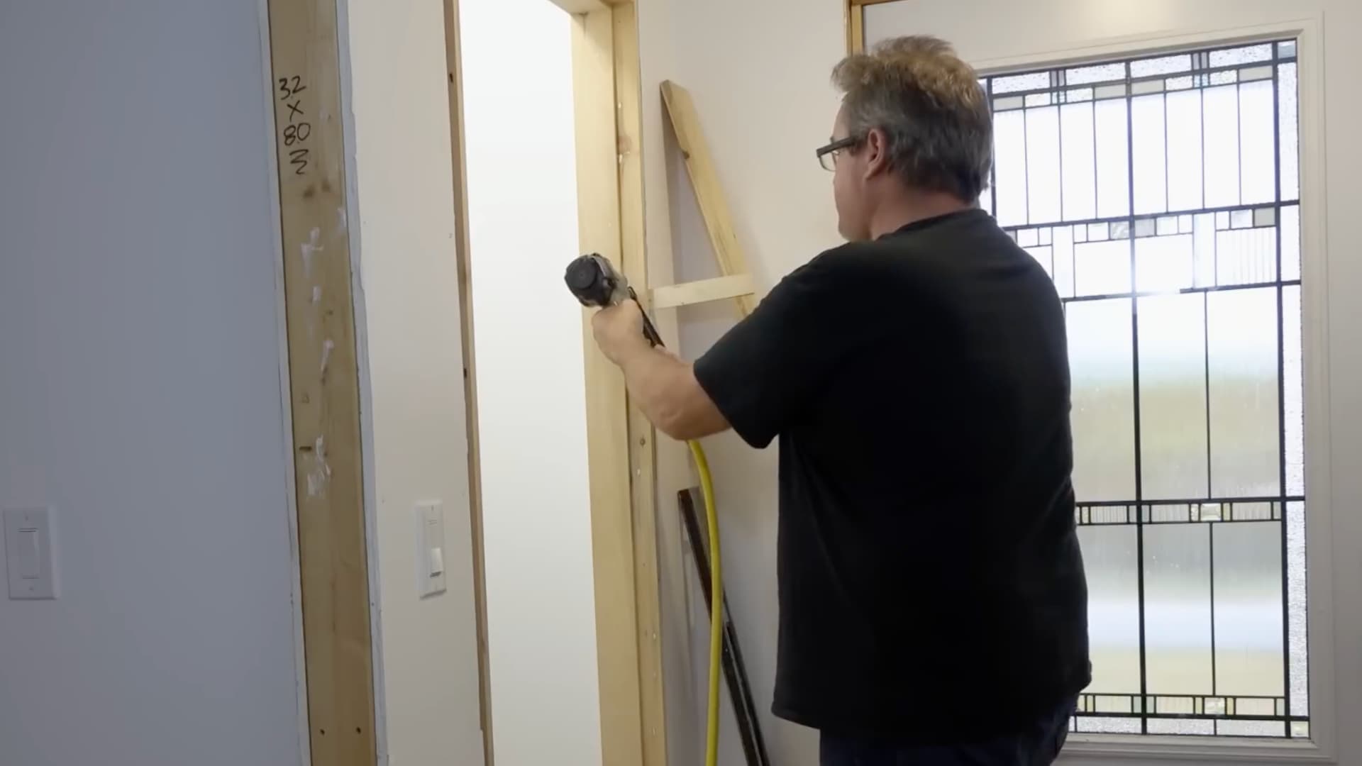 man using nail gun to set the second jamb with spacer board holding position