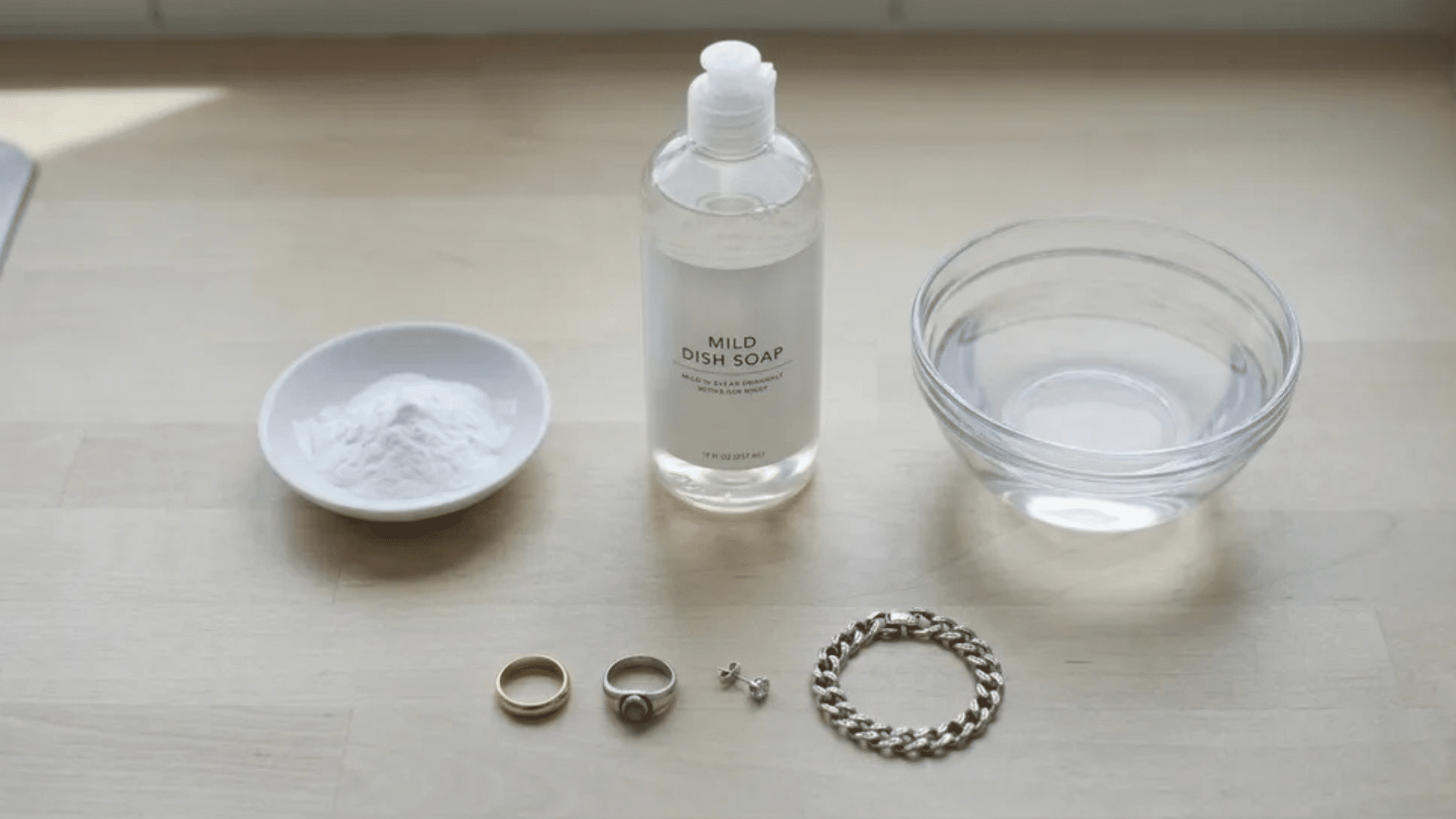 mild dish soap, baking soda, water, and assorted jewelry ready for cleaning
