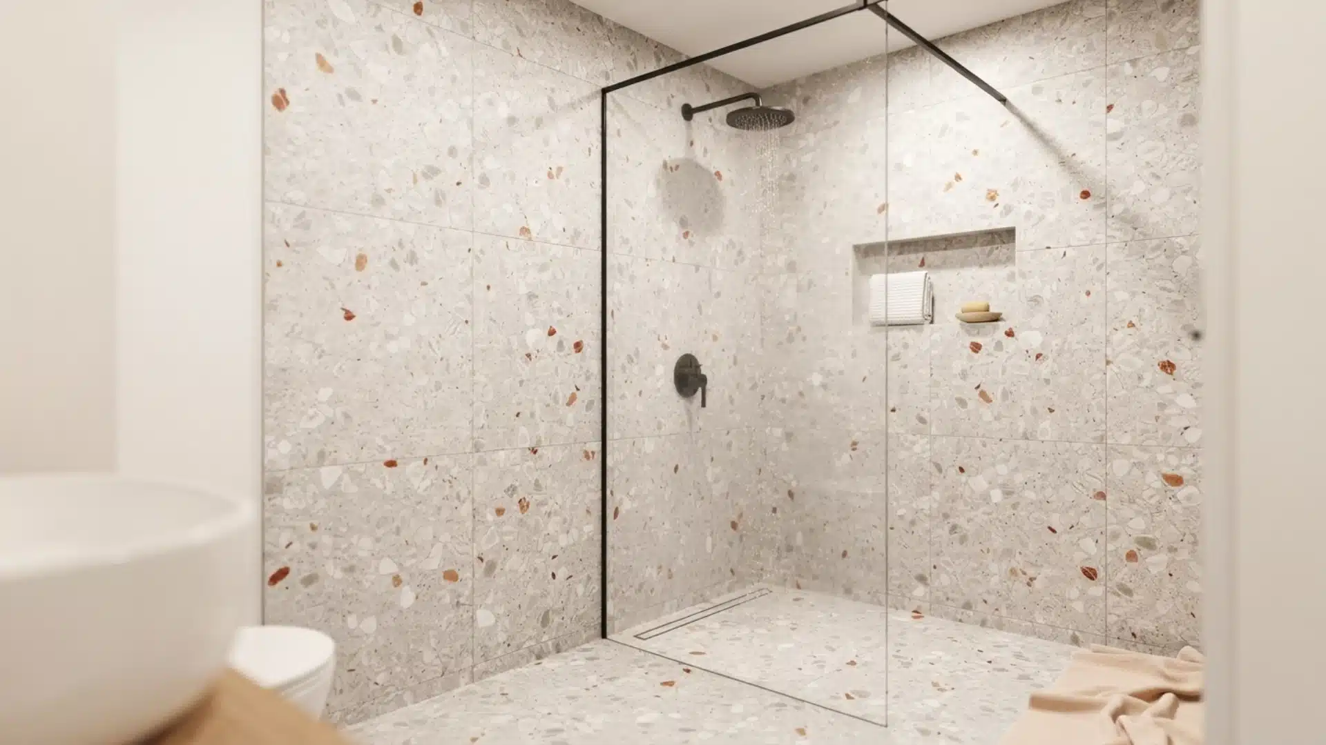 modern walk-in shower with light terrazzo tiles, black fixtures, and a glass partition wall