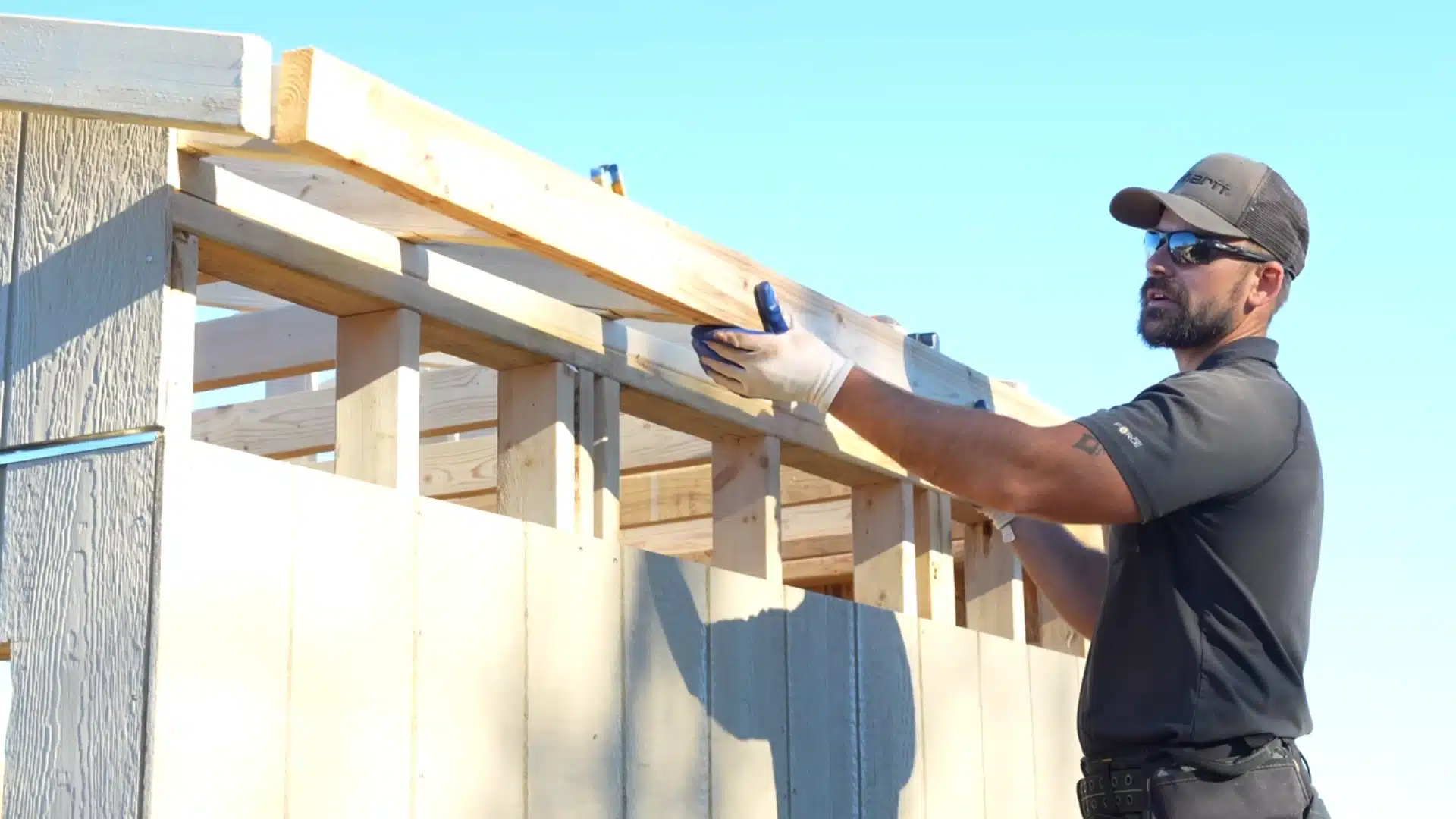 overhang and sub-fascia installation showing man securing wooden boards to roof