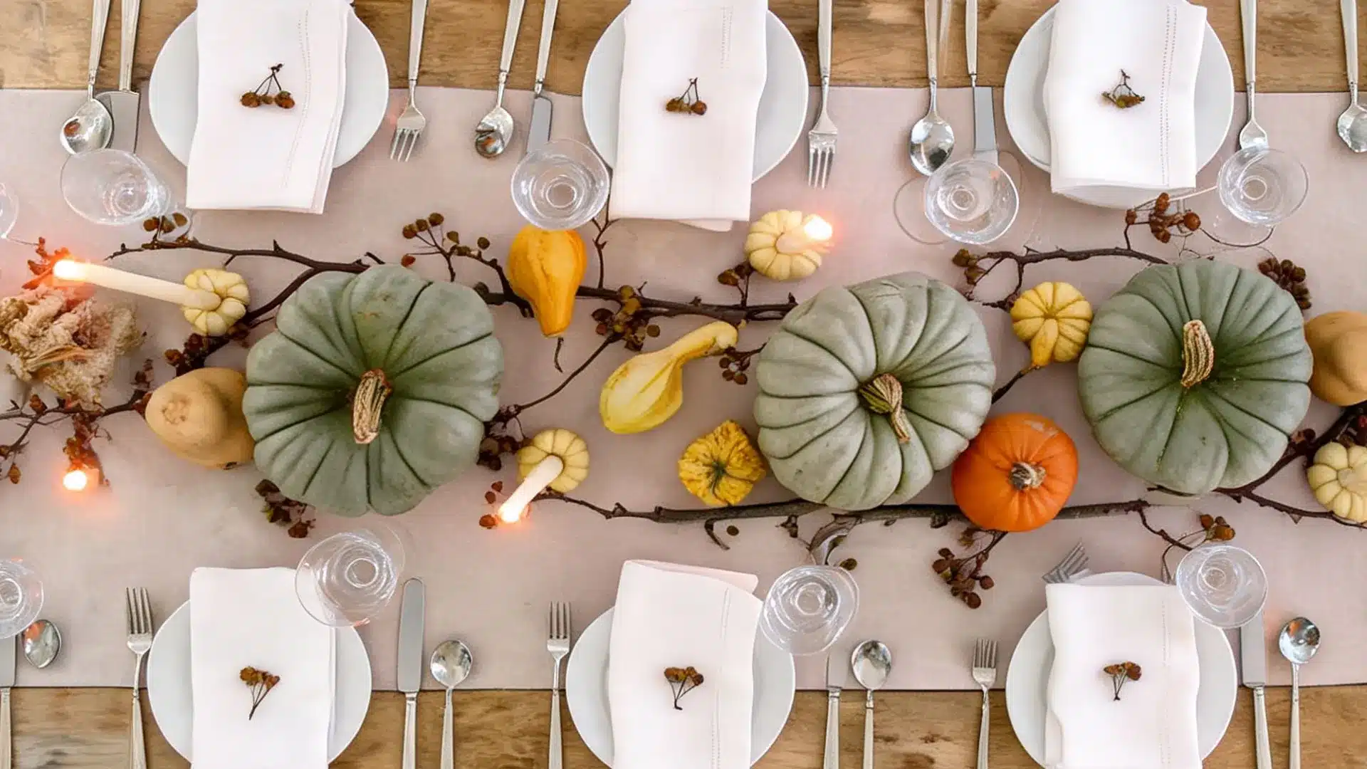 overhead view of thanksgiving table with heirloom pumpkins, gourds, branches, and lit taper candles
