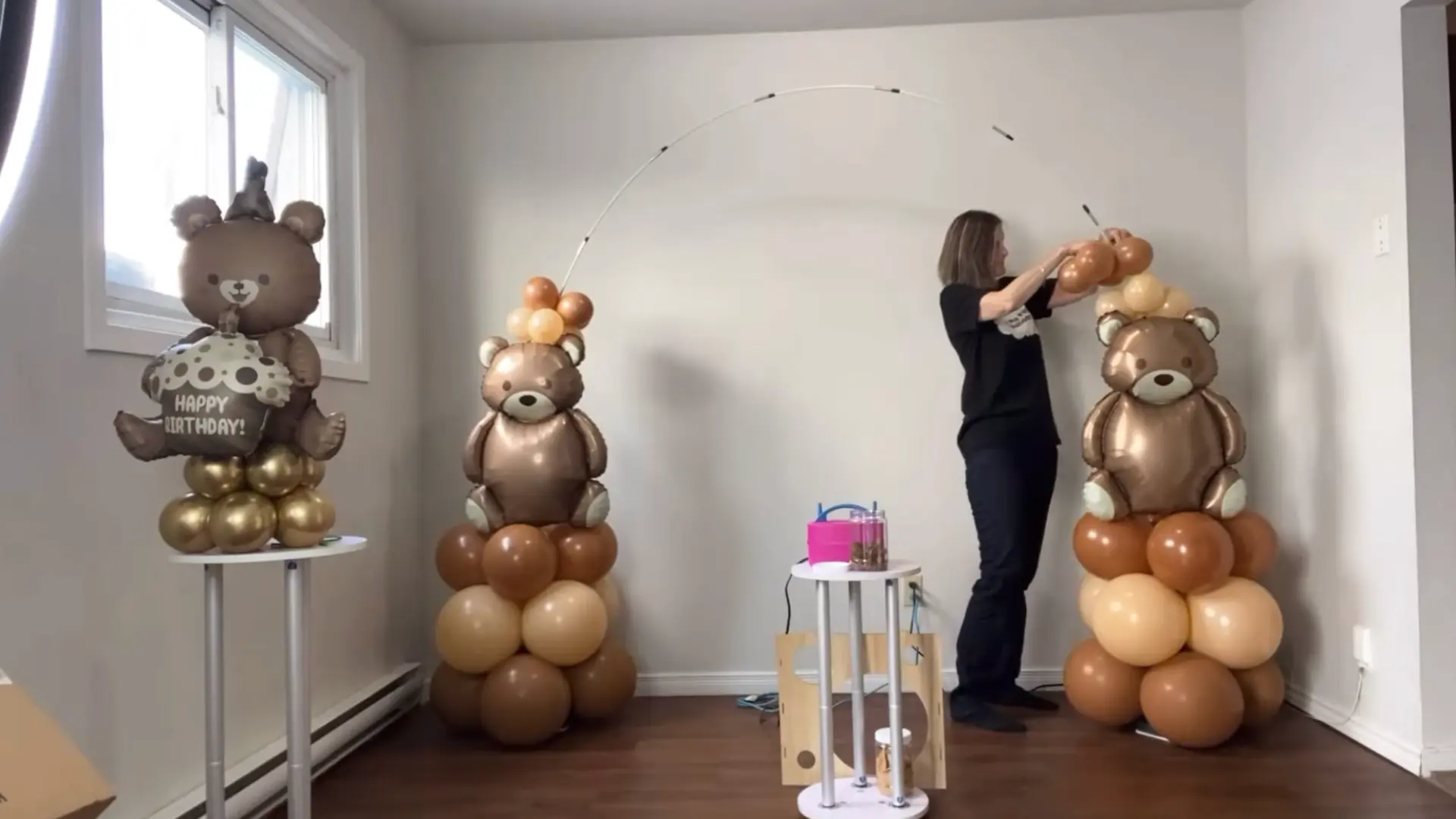 person adjusting balloon clusters and decorations on the right side of the arch frame